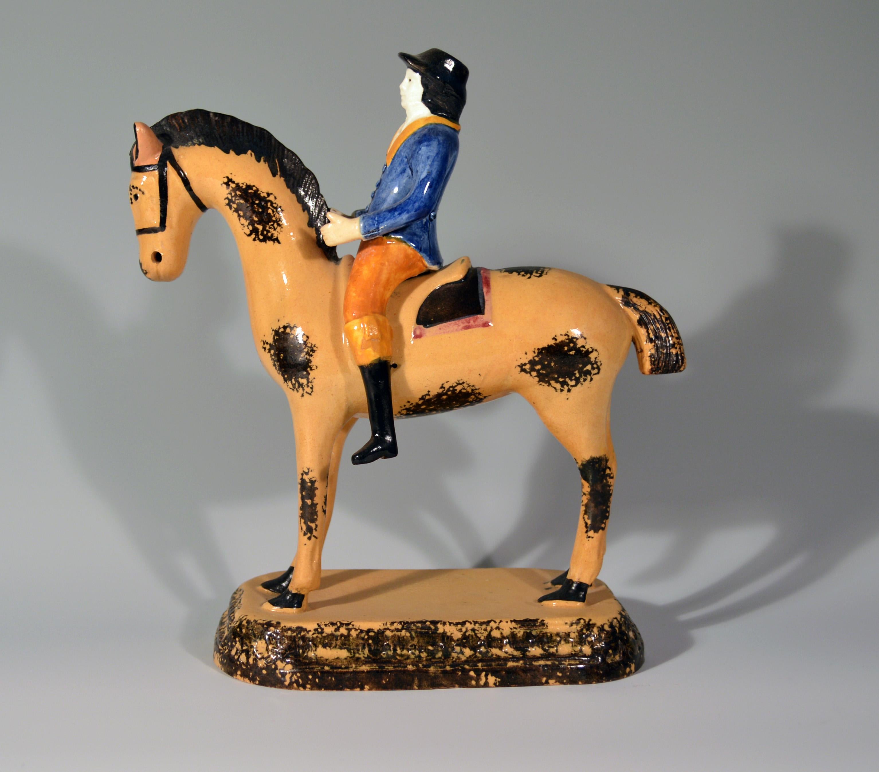 Prattware Pearlware Large Figure of Horse & Rider, Yorkshire, circa 1800-1825.

The large rare figure depicts a rider mounted on the back of a horse. The horse, dun-coloured with black splotches, stands on a rectangular shallow-domed rectangular