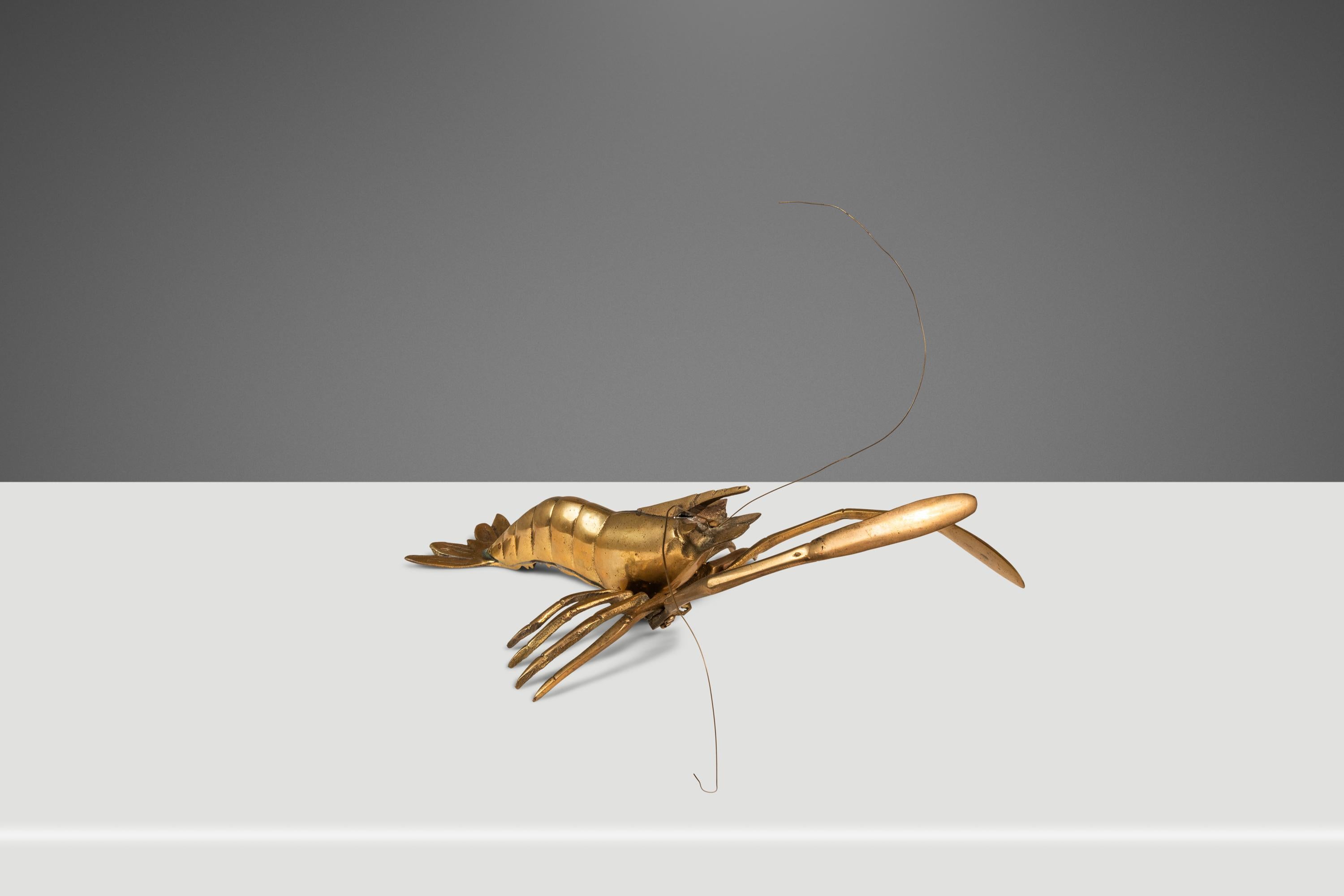 Voici une sculpture artisanale aussi complexe qu'elle est ludique et accrocheuse. Forgée en laiton massif, cette fascinante sculpture d'une crevette peut être exposée sur une table ou accrochée au mur. Anatomiquement détaillée, dotée d'antennes qui