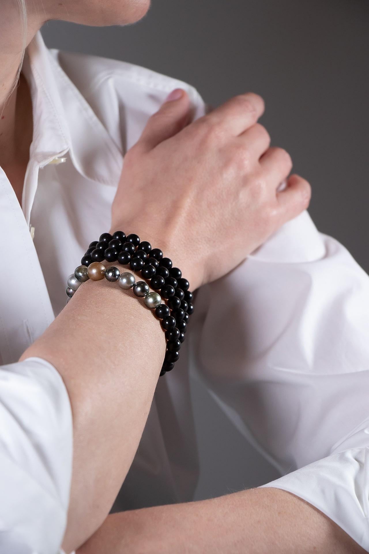 Ce bijou s'inspire des colliers de prière bouddhistes. Il peut être porté en collier ou enroulé autour du poignet. Il est captivant avec ses intrigantes perles de Tahiti naturellement colorées. 
Un bijou à la fois élégant et simple.
Les perles