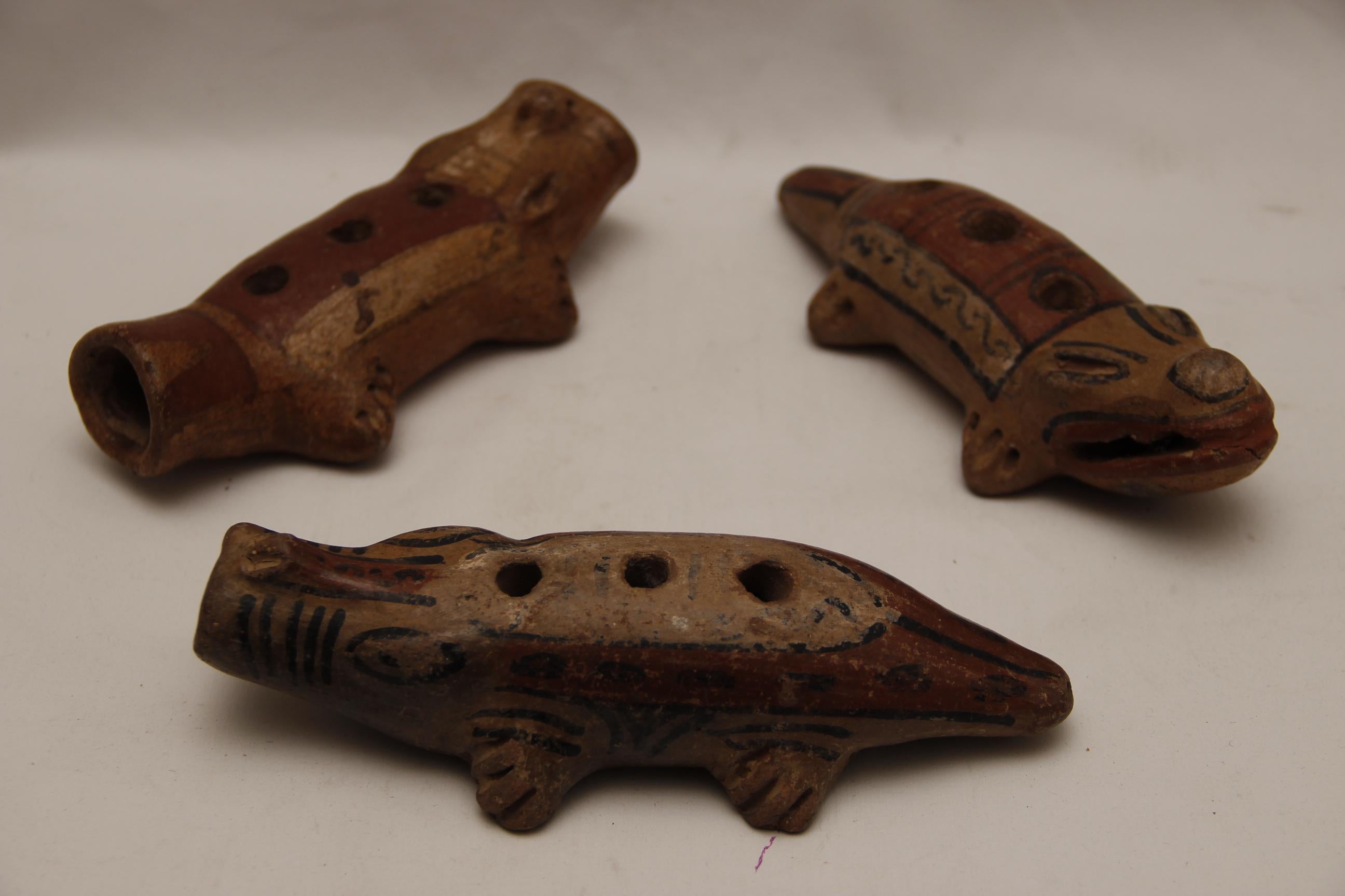 This grouping of alligator-like or crocodile effigy antique pipes is both beautiful and intriguing. The wear on the backs and underside of the polychromed pottery suggests handling and use over the decades. The top parts of the instruments are
