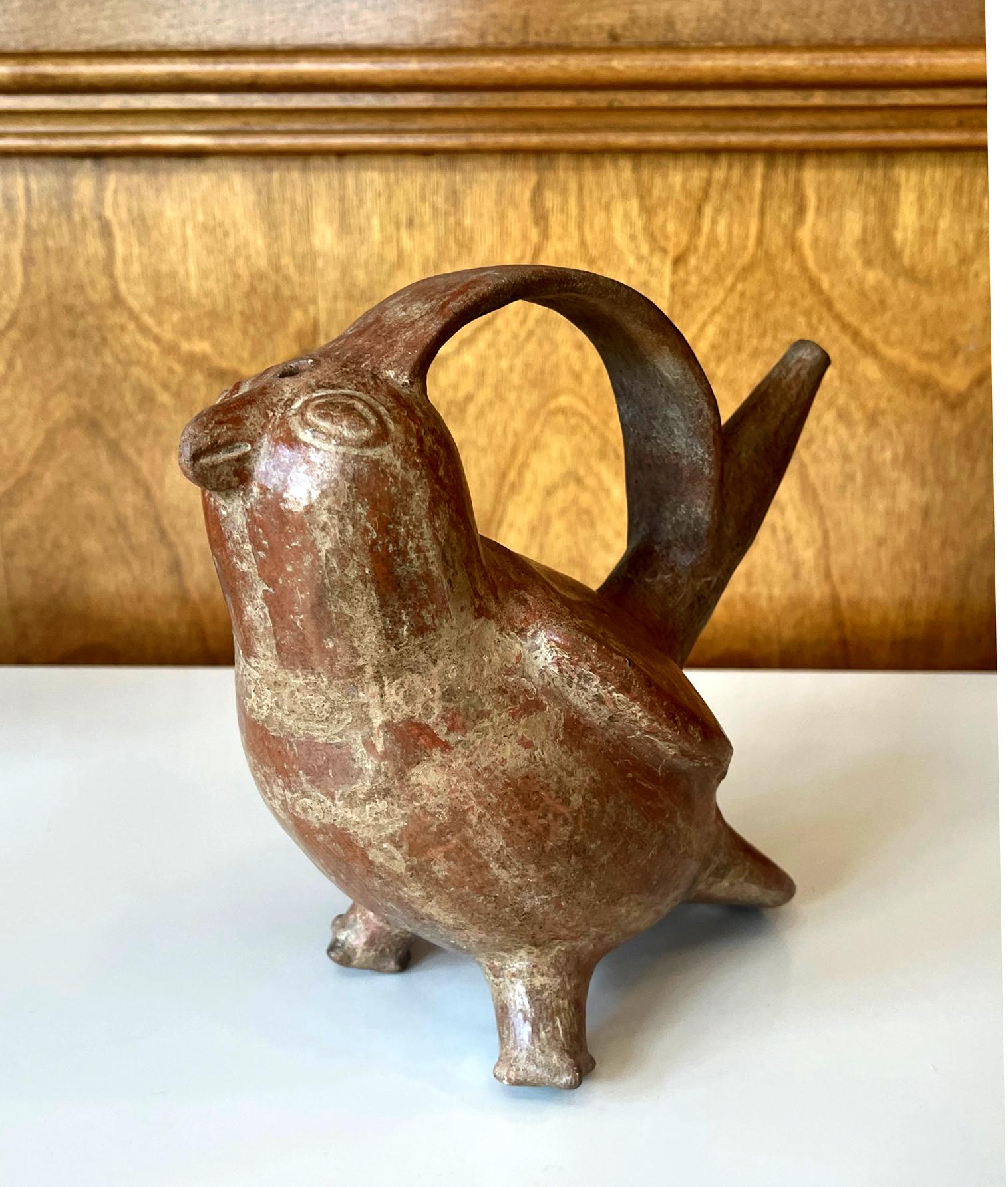 A pre-Columbian ceramic bottle in the shape of a bird from Northern Coast of Peru likely Sican Culture that flourished from 8th to 14th century. The avian vessel features a hollow body with a long sprout on its back that connects the head with an