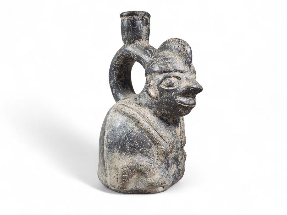 Pre-Columbianisches Gefäß aus der Chavín-Kultur in Form eines sitzenden Mannes, wahrscheinlich eines Jägers, mit einem Tier auf dem Rücken.
Die Kunst des Chavín ist bekannt für ihre komplexe Ikonographie und ihren mythischen Realismus. In allen