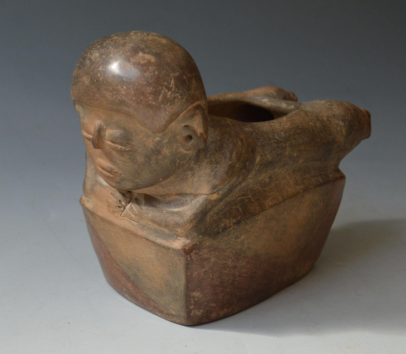 Buque nadador precolombino Chorrera

Cultura Chorrera Circa 800-400 a.C. Ecuador.

A  recipiente rectangular coronado por un  personaje yacente en pose de nadador con tocado estilo casco de ojos de grano de café pintado en rojo, la parte inferior