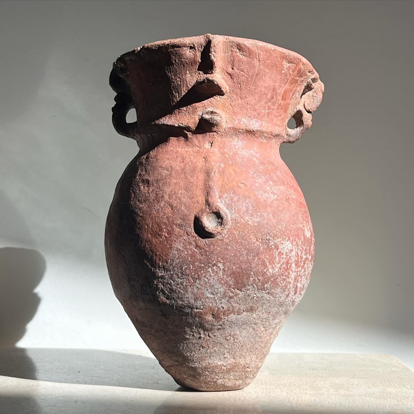 A Pre-Columbian pottery vessel. There are hand-sculpted vestiges of a face reminiscent of early figurative efforts. Patina includes traces of red cinnabar and mineral deposits, attesting to the item’s age. When wetted, there is an exquisitely