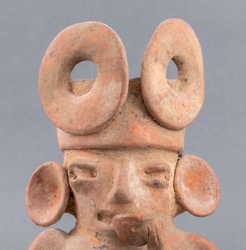 Ancient pre-Columbian, Colima, Mexican, circa 100 BCE to 250 CE, ceramic pottery redware vessel in the form of a seated figure holding a cup to his mouth and wearing large earplugs and elaborate headdress. 11.75