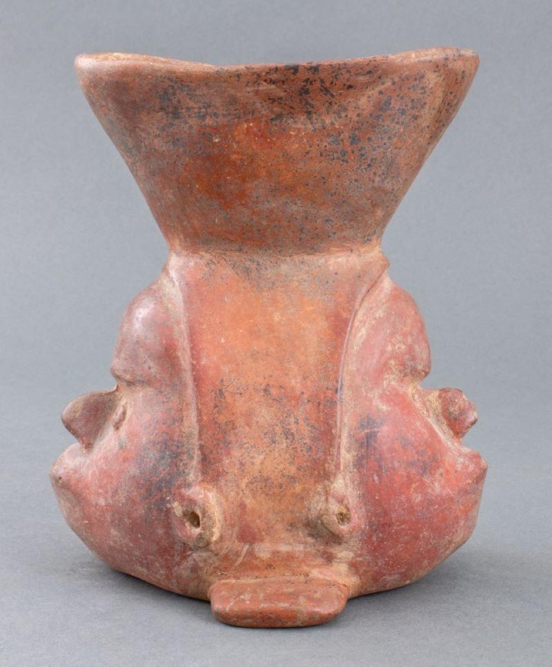 Ancient pre-Columbian, Colima, Mexican, circa 100 BCE to 250 CE, ceramic pottery redware vase, the base in the form of two heads, with pierced eyes and ears and wearing headdresses, surmounted by a flaring spout. 7.5