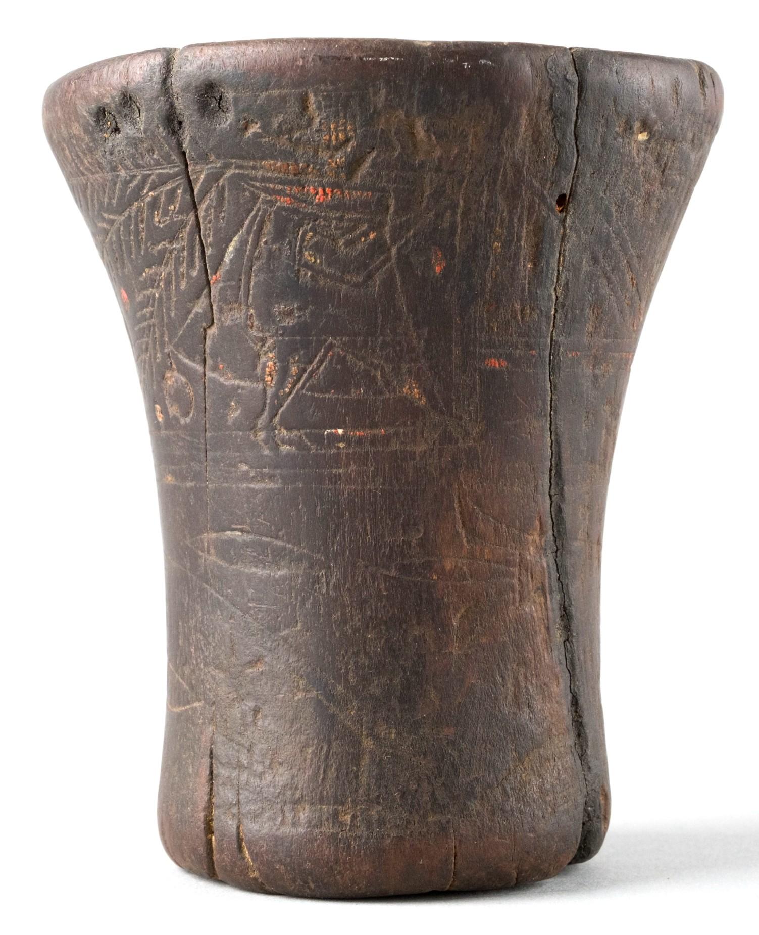 The hand carved beaker-shaped wood drinking vessel was used to drink 'chicha' which was a beer-like beverage made from fermented corn. The weathered exterior showing incised geometric & figural motifs, accented with traces of original hand painted