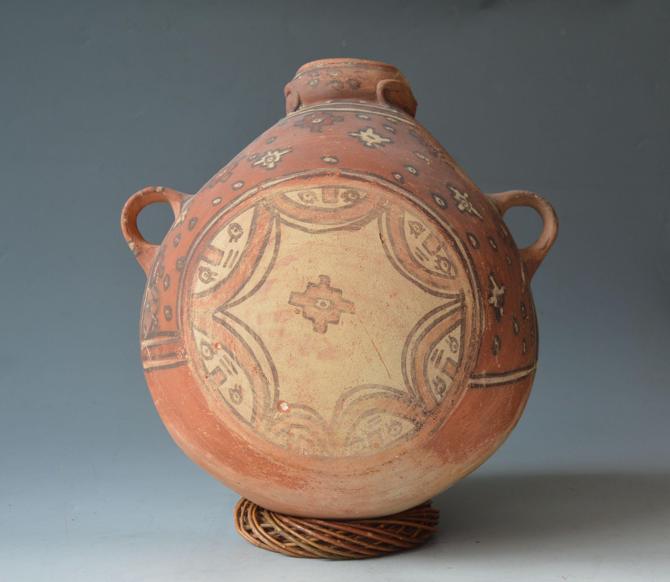Pre Columbian Large Huari Canteen vessel South  American Antiques

A rare impressive large bulbous canteen type vessel skilfully painted  in polychrome colours with large circular geometric pattern with scalloped semi circles containing faces, 
the