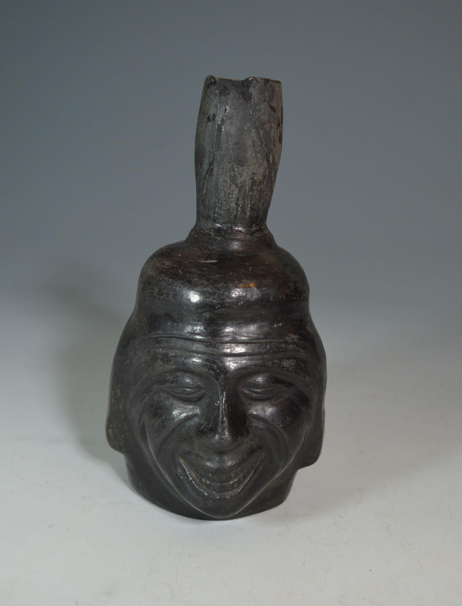 Pre Columbian fine Inca grey ware portrait head vessel ancient South America
A portrait head vessel of a smiling man wearing traditional Inca cap
Inca period, circa 1438-1532 AD, Peru.
Condition: minor surface wear, minor spout