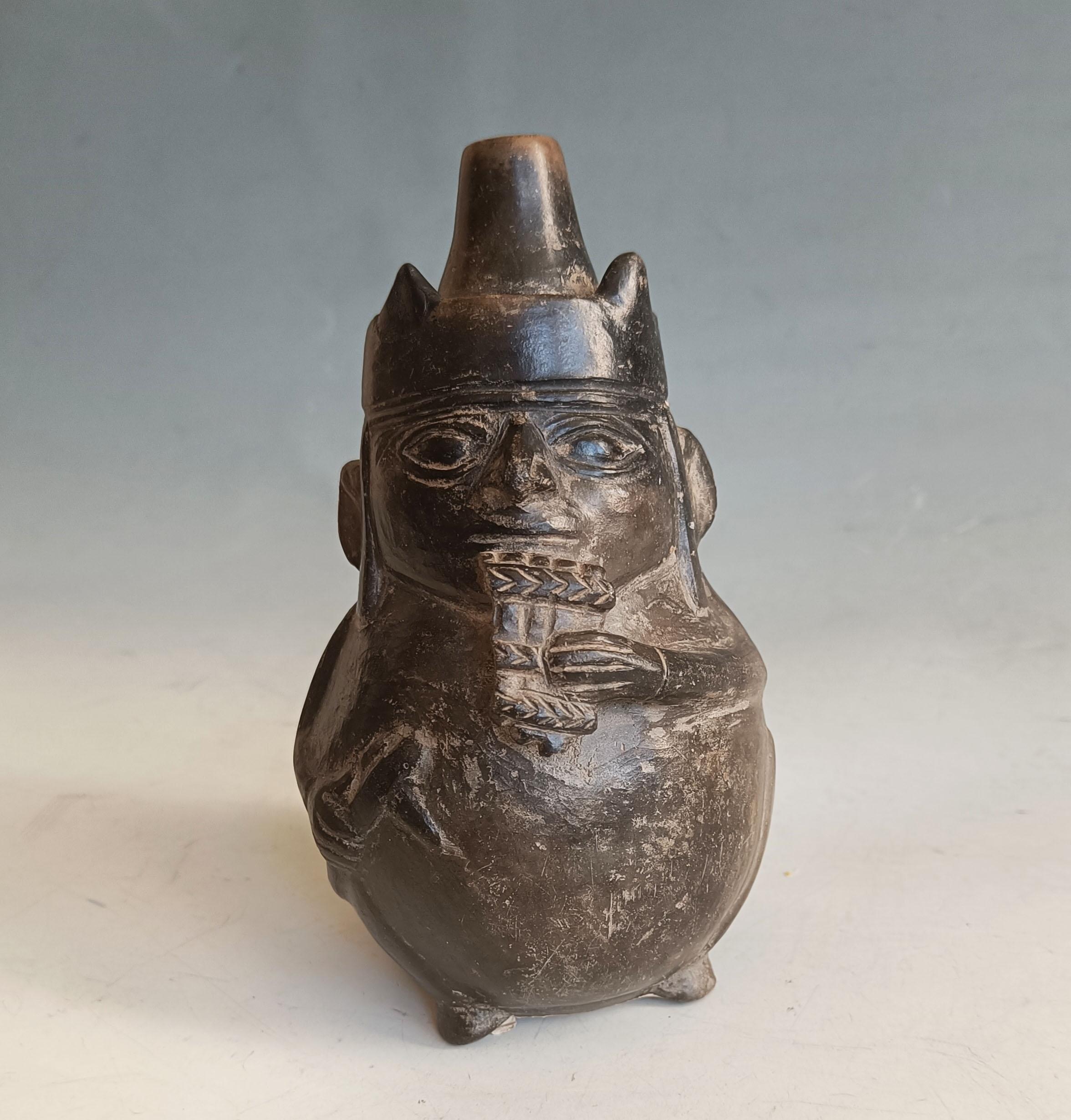 
Rara vasija moche precolombina con retrato -  Músico con zampoñas - Perú, 700-900 d.C.

Excepcional e insólita vasija retrato moche precolombina de loza gris, que representa a un diminuto y rotundo personaje tocando la zampoña. Esta rara cerámica