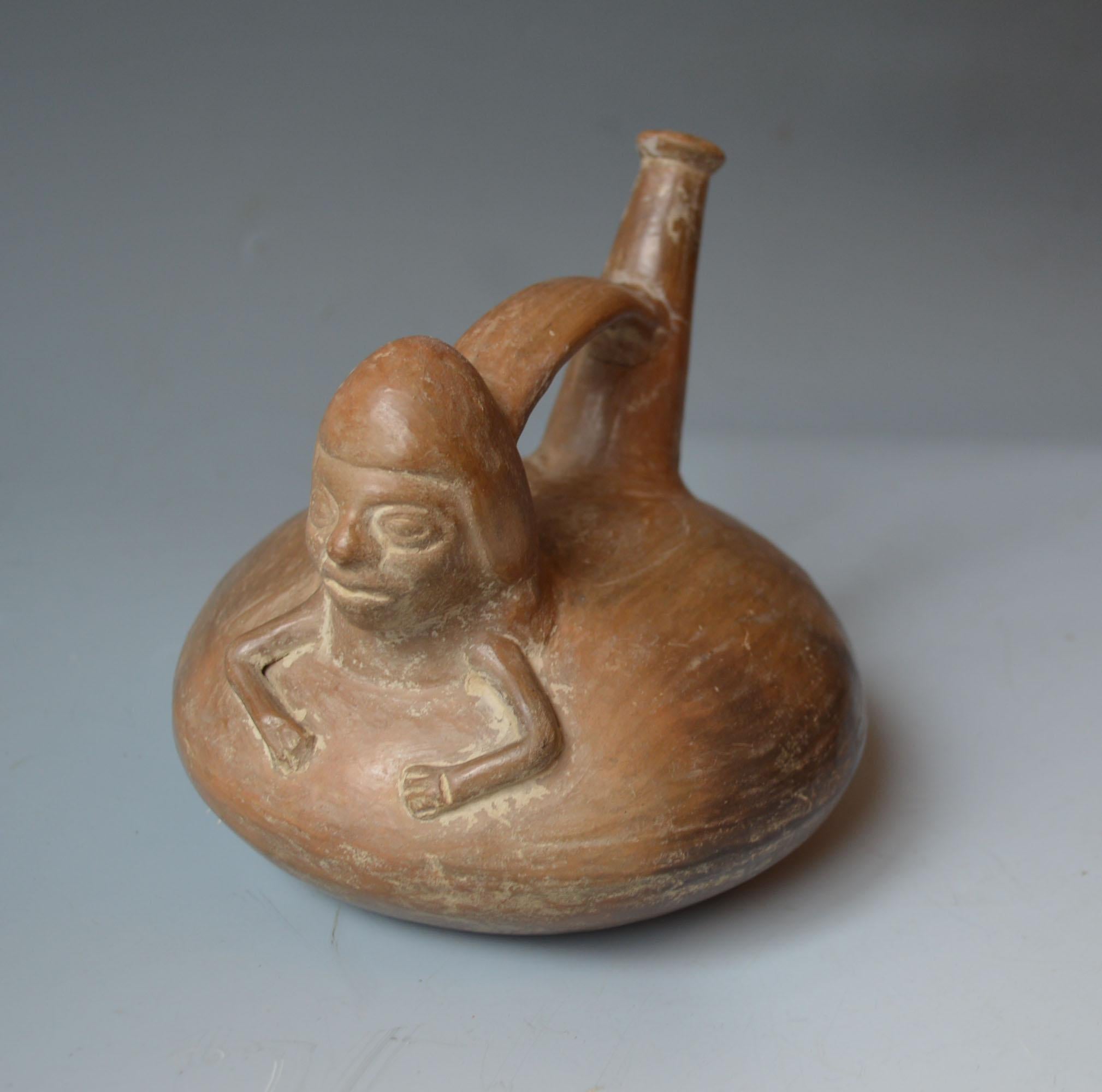 A Pre Columbian Inca stirrup vessel

Brown ware terracotta stirrup vessel surmounted the head and torso of a man with Traditional style Inca Cap

Inca Peru C 1400-1533

W 17 cm H 15 cm.

Condition : Top of spout has been reattached otherwise