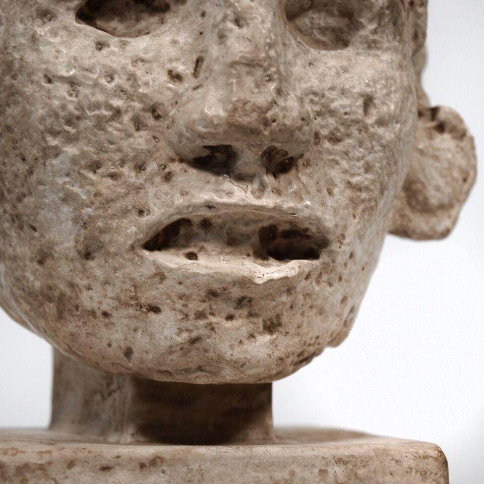 An antique plaster head modelled on a Mayan original, dating from the mid-20th century. Indecipherable signature at the back of the neck.
D 13 W 13 H 22 cm.