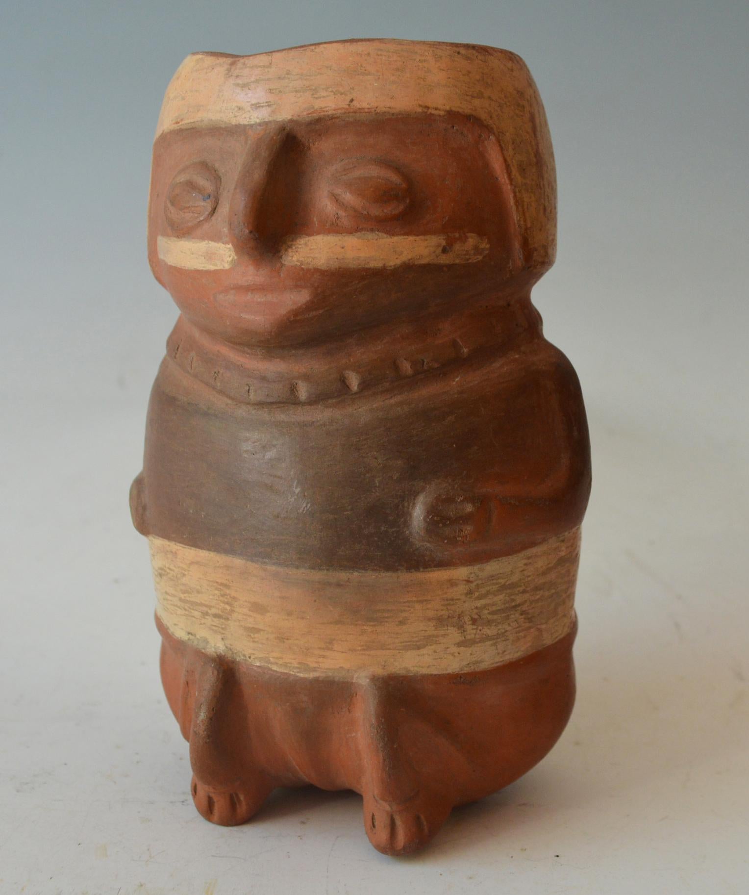 A Pre Columbian Moche vessel of a personage with a large nose ornament, sitting
with sublime expression probably representing a psychotropic induced state.
 Condition: Fine, collection numbers on back and base
Size height 18 cm,

Pre-Columbian,