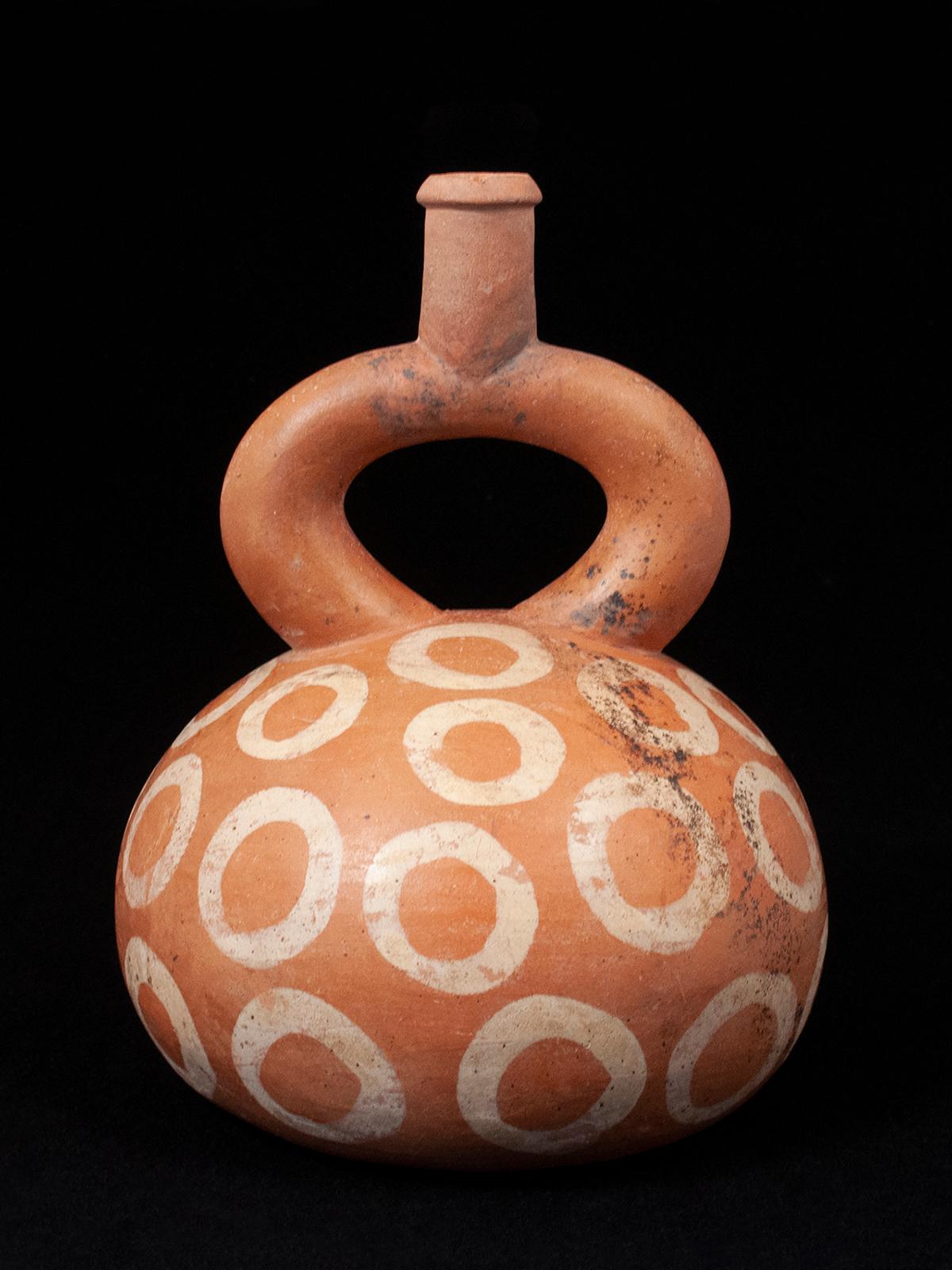 Pre-Columbian Moche stirrup vessel with cream-colored Circles, Peru

A graphic terracotta stirrup vessel with cream slip painted circles, with some natural mineral deposits. Measures: 5.5 inches (14 cm) diameter, 7.25 inches (16.4 cm) high.
Ex.
