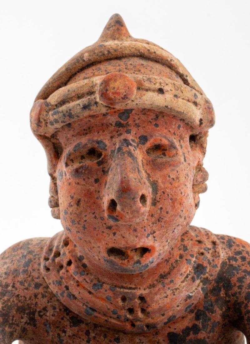 Ancient pre-Columbian, Nayarit, Mexican, circa 100 BCE to 250 CE, hand-built ceramic pottery redware sculpture of a seated male figure with arms crossed and wearing a headdress and multi-strand necklace. 9.75 H x 5.5