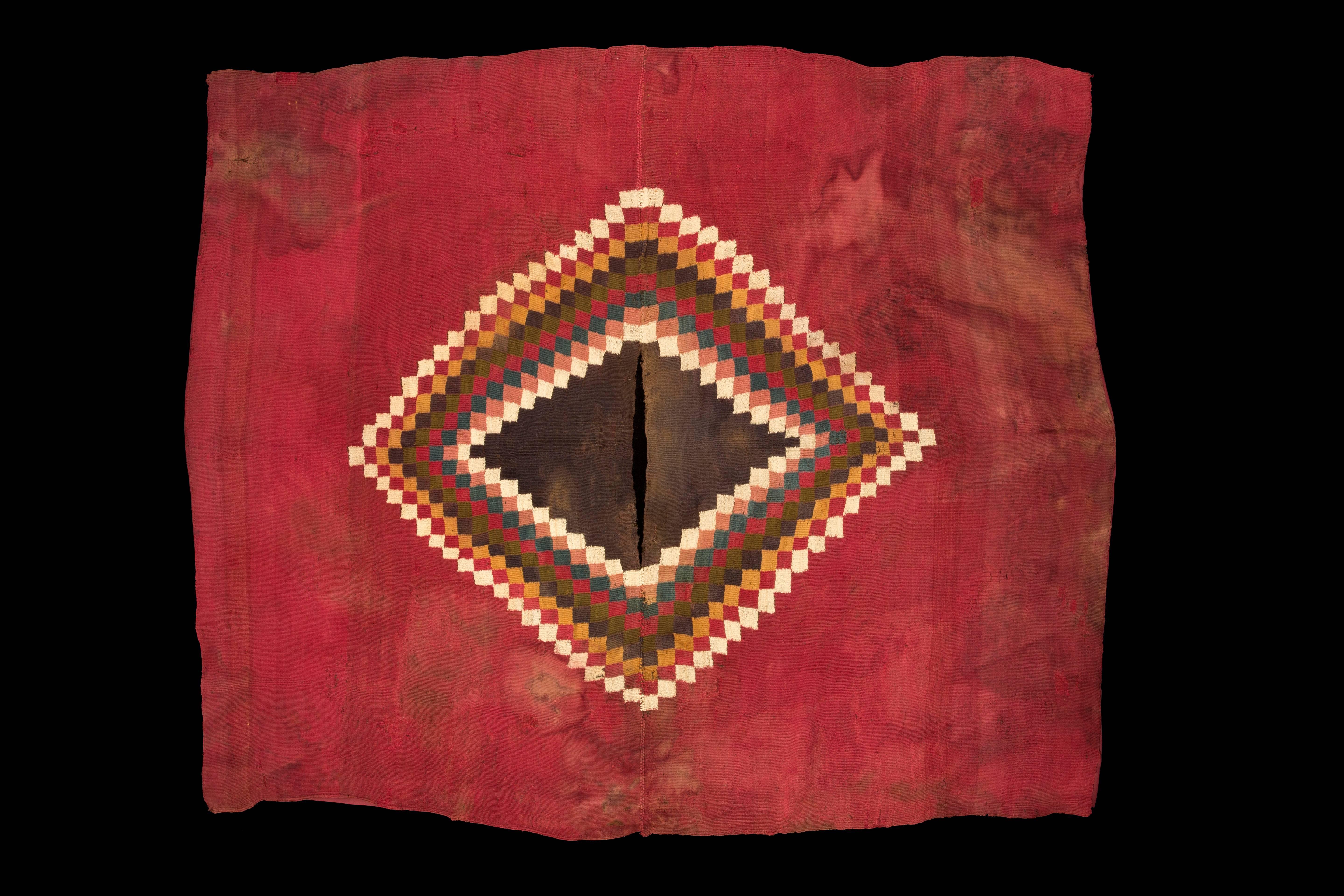 Complete Nazca Unku in vibrant red with blue, green, yellow and white squares forming V design around the brown neck opening. The multicolor squares in stepped design make a diamond shape when the unku is open.

200-300 CE

Nazca, Peru

Size: