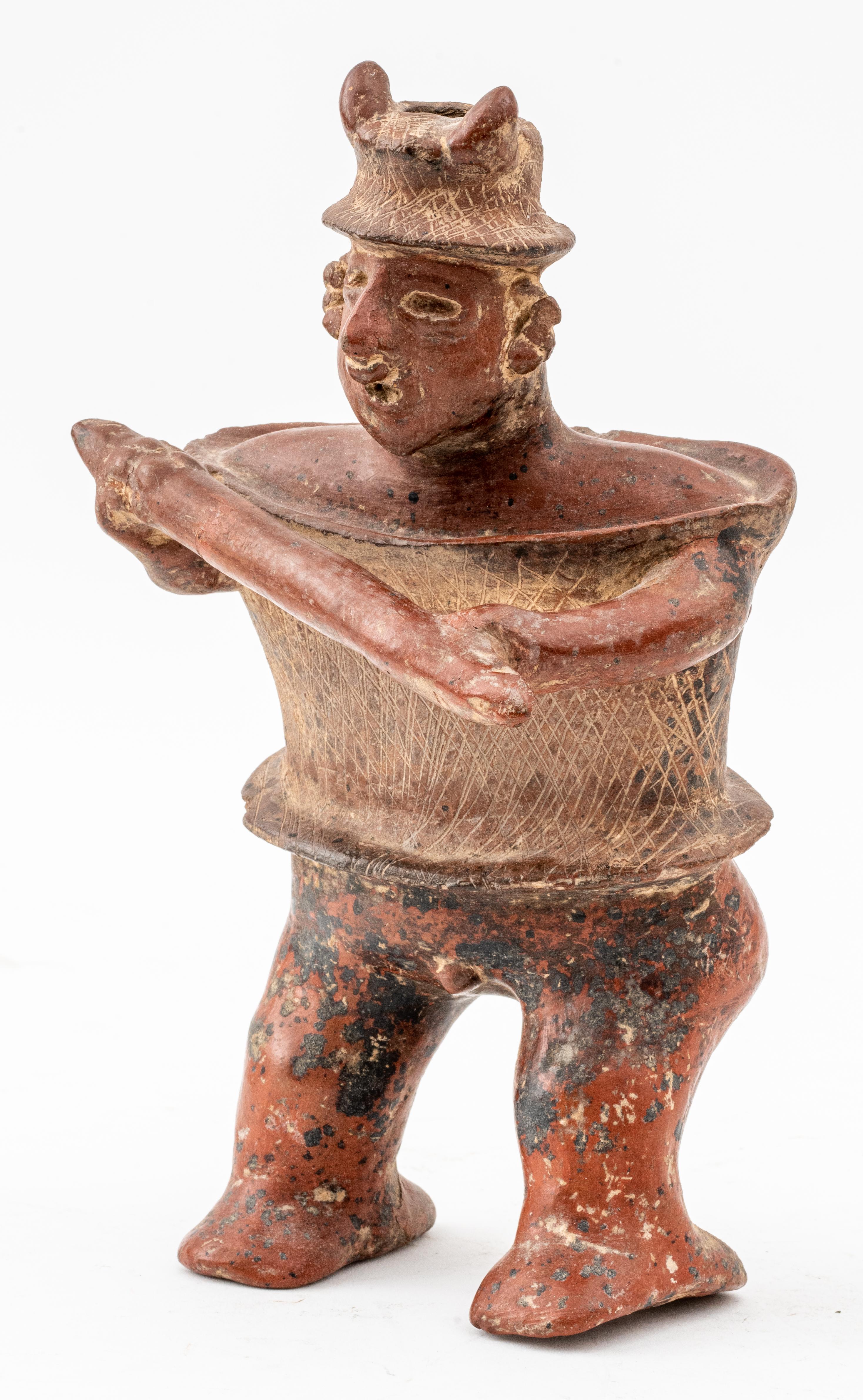 Ceramic redware figure in the form of a warrior wielding a staff, textured etching to hat and breastplate, spout opening at head, probably pre Columbian earthenware.

Measurements: 11
