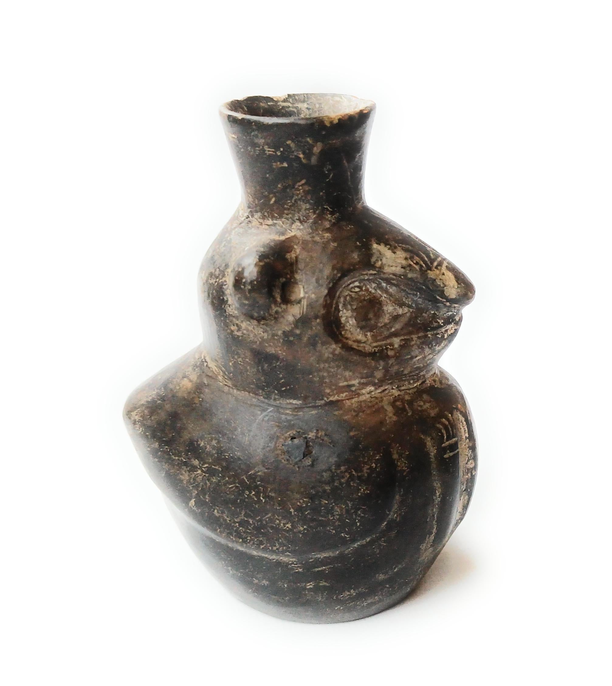 Pequeña vasija de loza gris muy bonita de un pájaro  transformándose en una criatura de tipo ardilla con las manos hacia delante, destacando el principio de dualidad representado a menudo en el arte precolombino

Vasija precolombina Chimú antigua