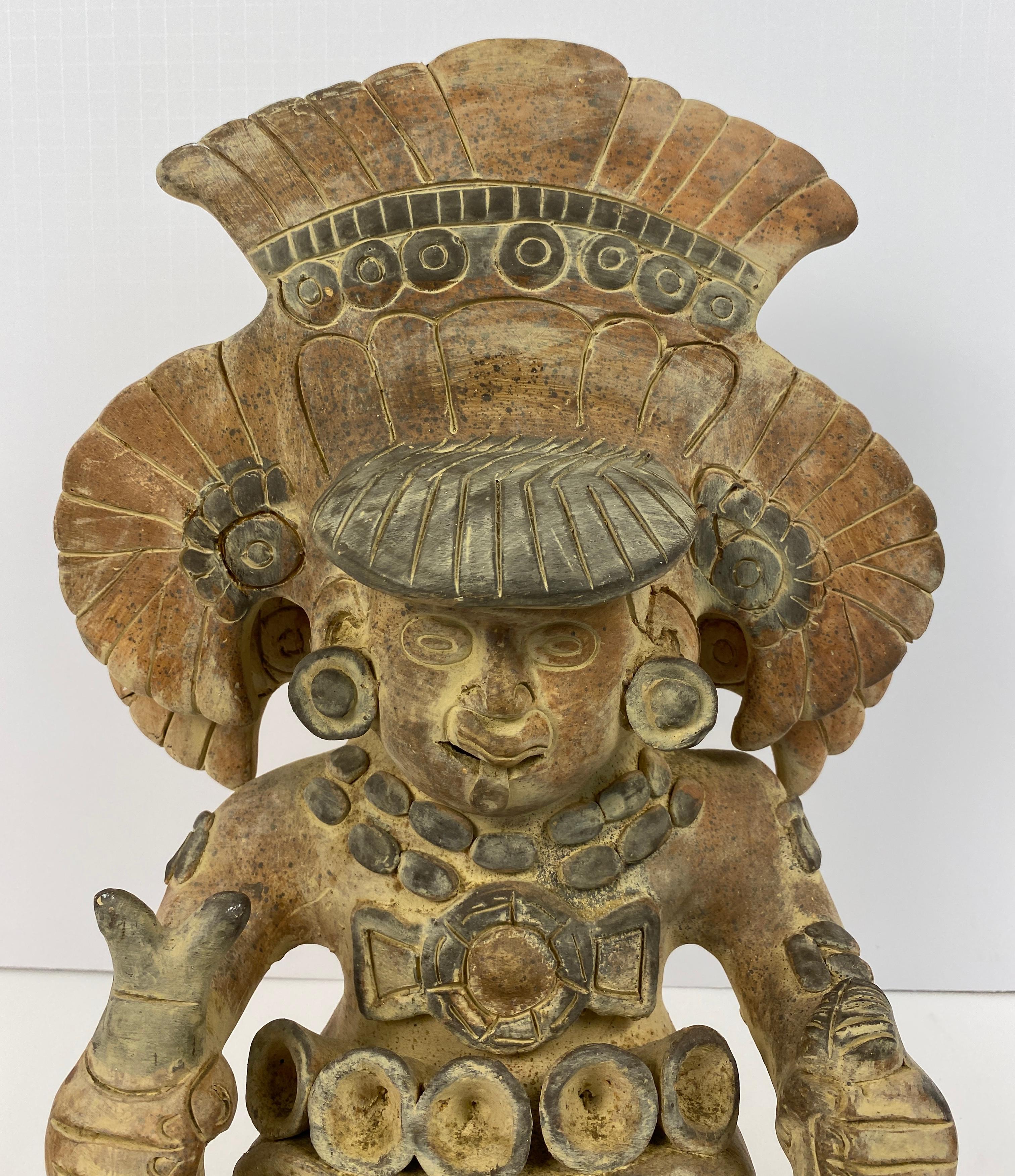 Figura primitiva mexicana de época, decorativa y bien proporcionada, que representa a un hombre sentado, con ropa detallada y estampada. La escultura mide 
16 1/4