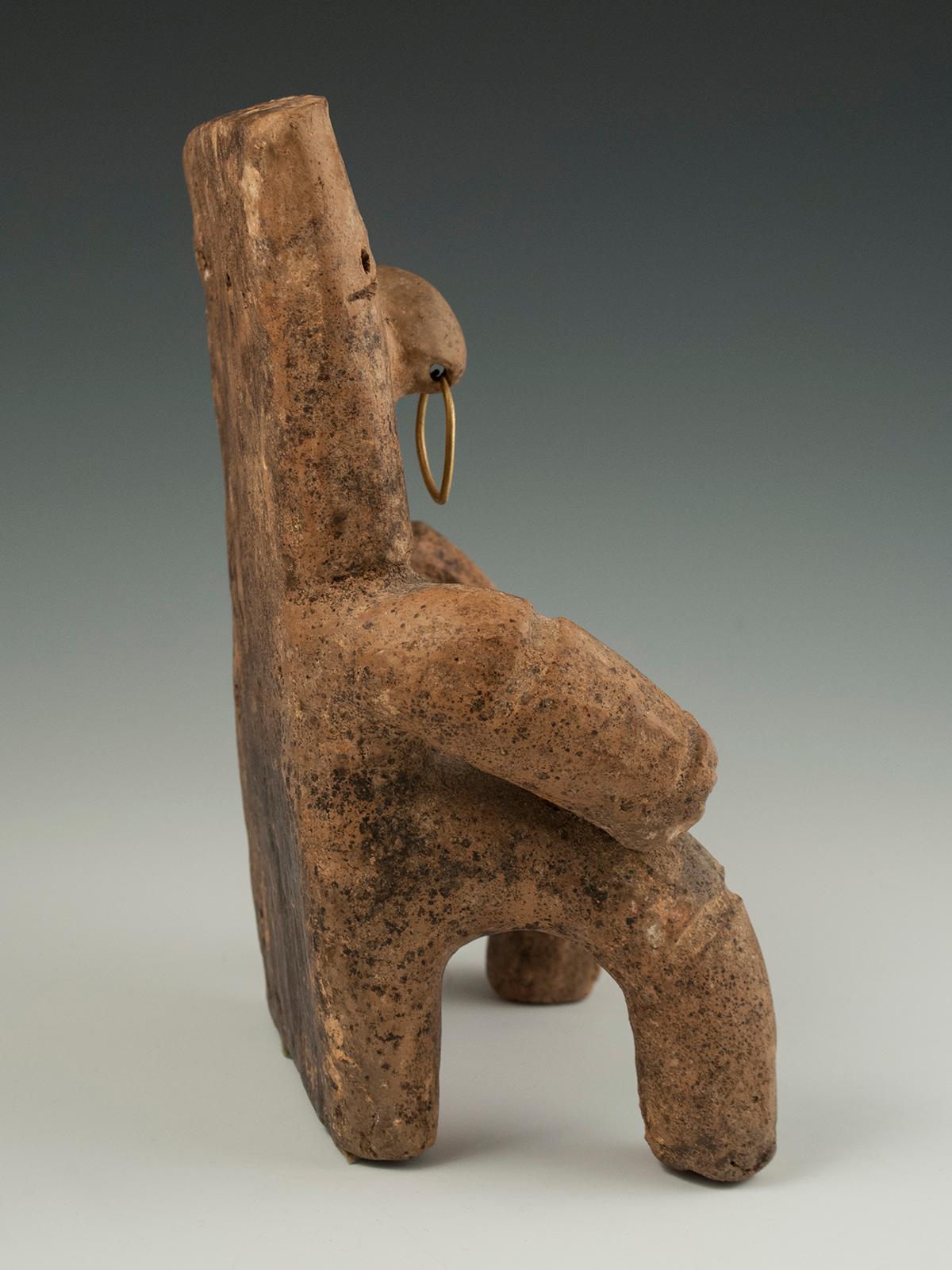 Pre-Columbian terracotta figure, Quimbaya culture, Columbia

A slab tomb figure sits with hands atop thighs, wearing a rather serious expression and a gold nose ring. There are the typical symmetrical holes, slit mouth and eyes, a belly button and
