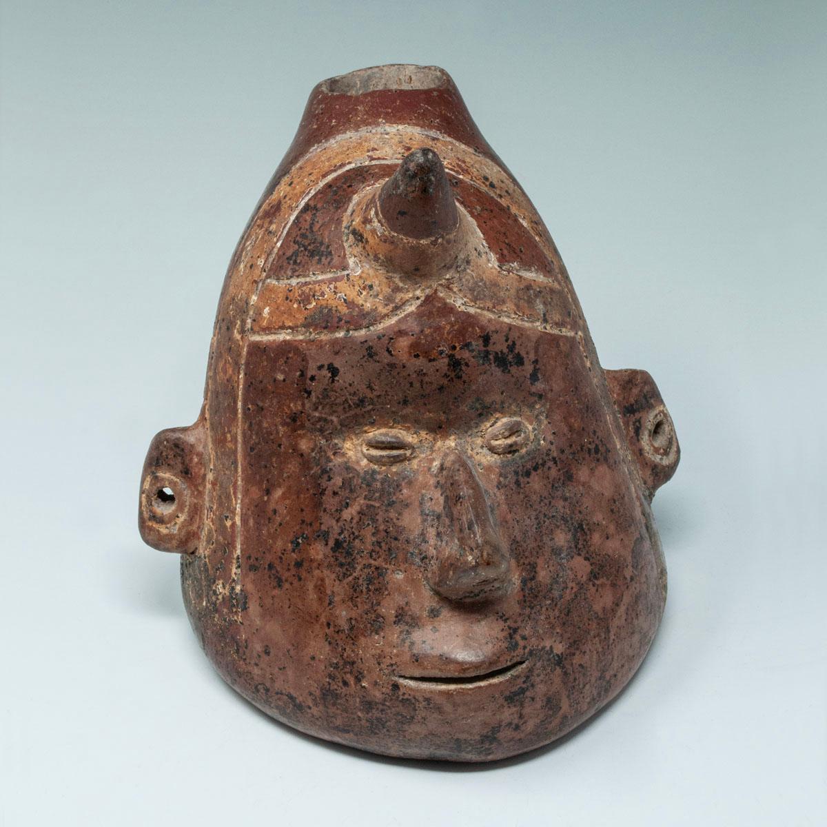 Vaso di terracotta Pre-Columbian, Colima, Messico occidentale

Una classica testa di sciamano con un corno legato alla fronte con una fascia dipinta a mano, occhi a chicco di caffè, naso appuntito e bocca a fessura. Le orecchie sono forate e nel