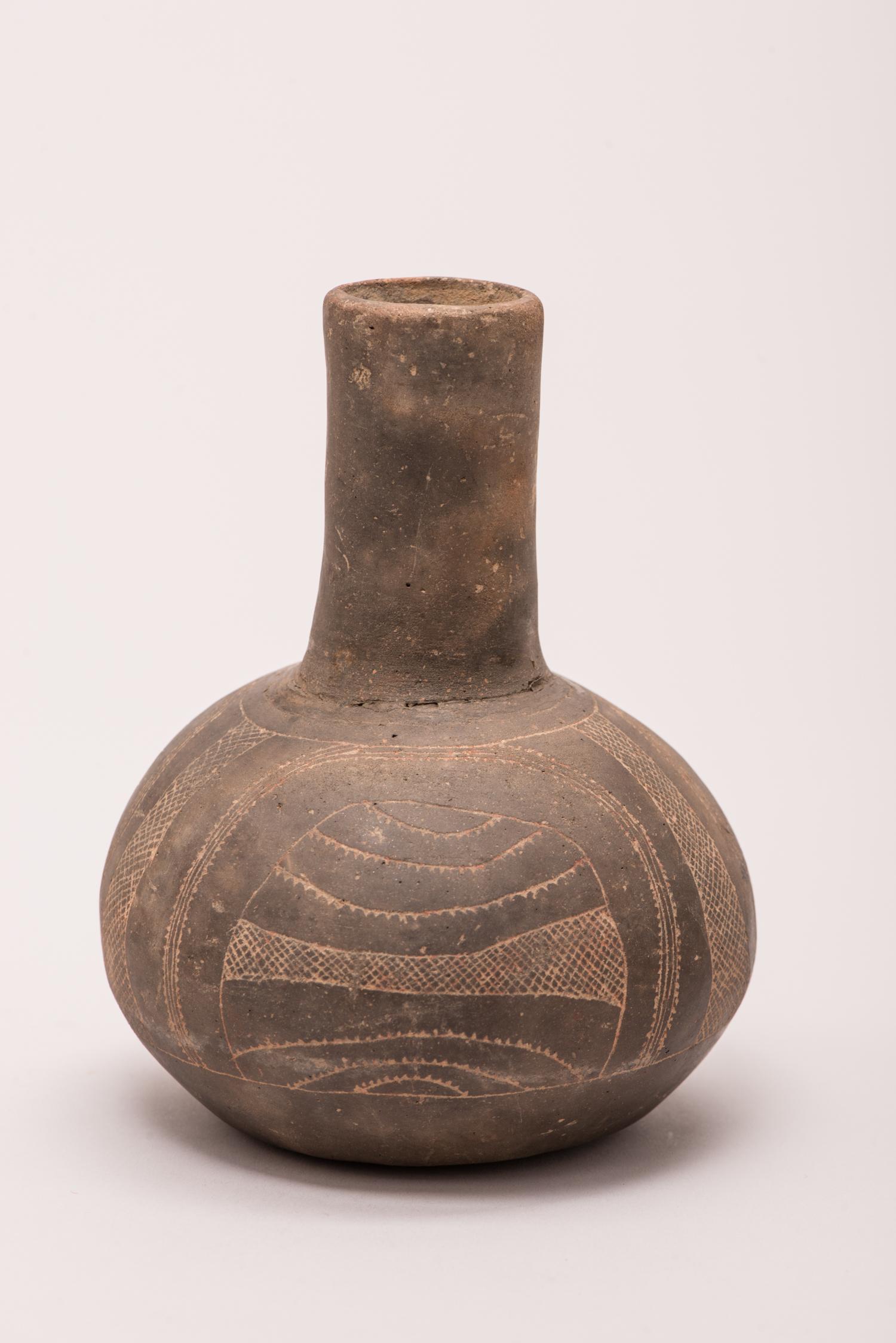 Engraved Ceramic Bottle    

Region/Tribe: Southeast, Arkansas, Oklahoma, Texas/ Caddoan Culture 

Circa: 700 AD - 1200 AD

Materials: Ceramic with feint remnants of red ochre

Dimensions: H. 6 3/4” x W. 5”

Condition: Overall Excellent.