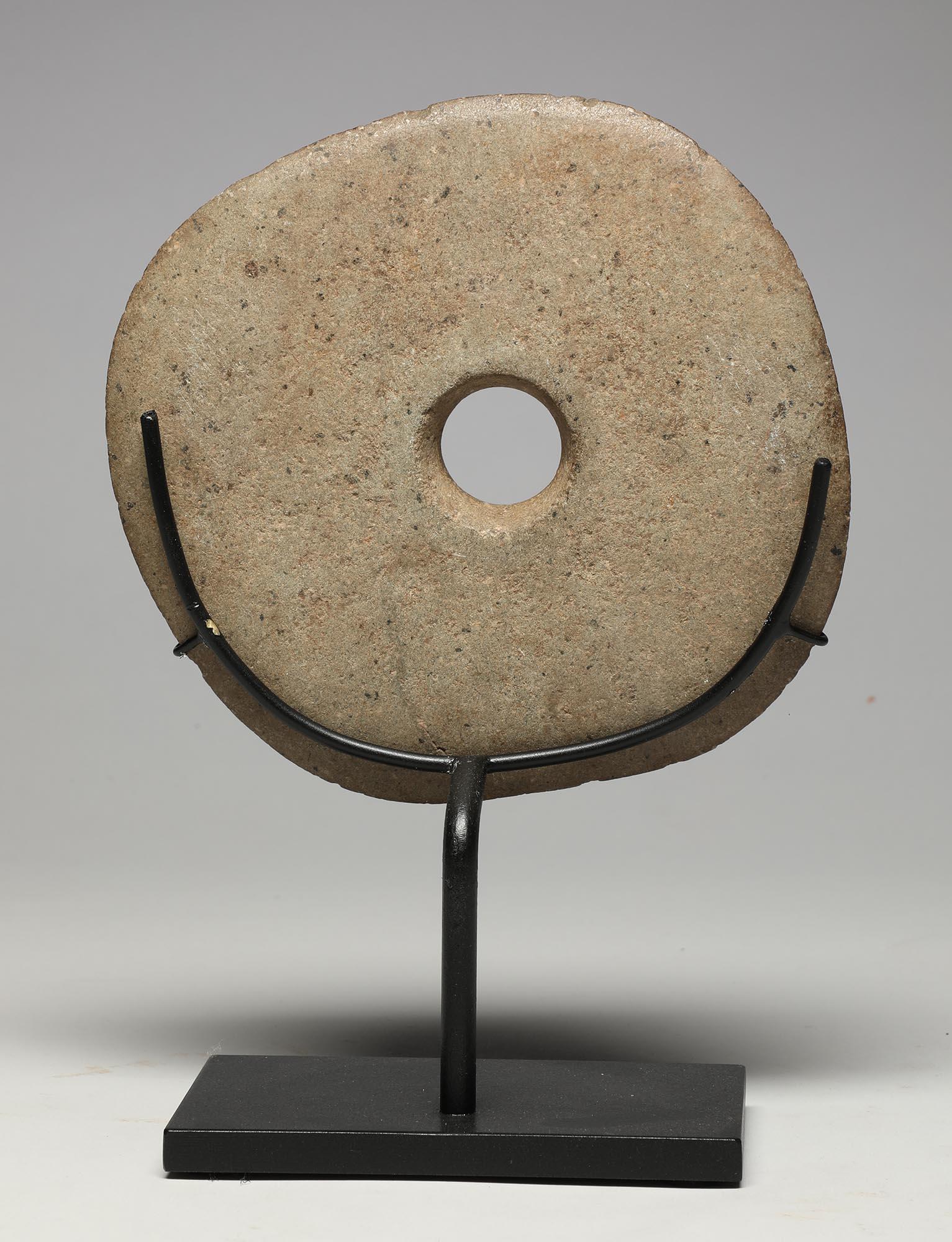 An early pre-contact ground stone disc mace head from New Guinea, with circular hole for attaching to a handle, simple raised shape around hole on one side. Early 20th century or earlier. Very modern and contemporary form with a smooth feel to the