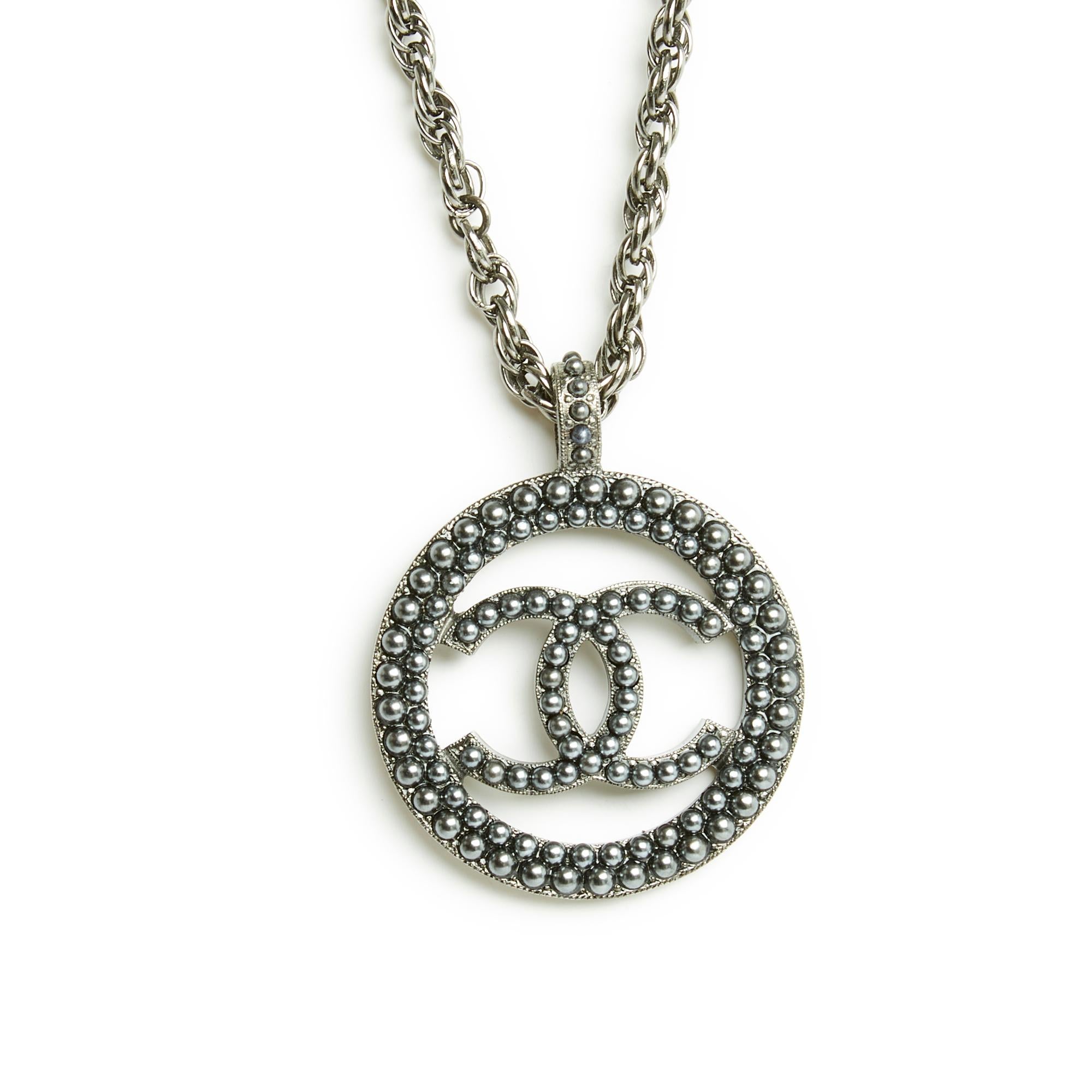 Chanel necklace Métiers d'Art collection at the Ritz or Pre Fall 2017 mid-length in blackened silver metal, composed of a cable knit chain and a large CC medallion inlaid with coordinated micro pearls, closure with a carabiner on a ring and its CC