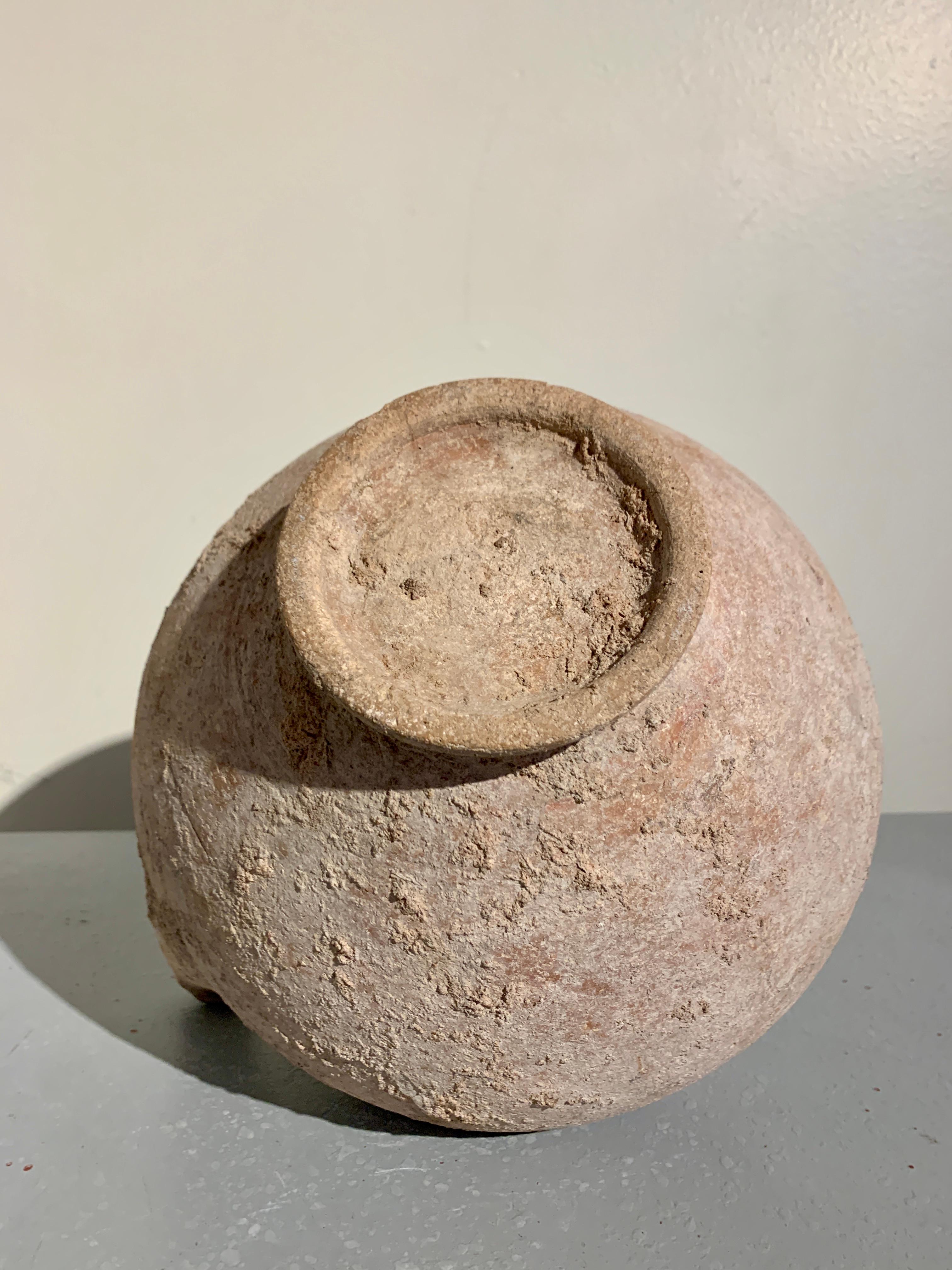 An evocative large pottery pouring vessel, kendi, pre-Khmer, 6th-8th century, Cambodia.

The large kendi of typical form, with a bulbous body set on a ring foot, featuring a single spout emerging from the shoulder, and a narrow, tapering neck