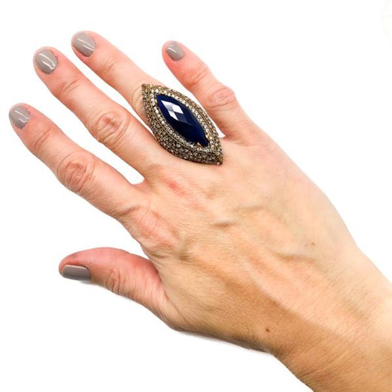 A striking pre loved Marquise Cocktail Ring. Featuring a large blue glass marquise stone surrounded by pave set crystals that twinkle beautifully when worn. Created with a gold tone metal top with a solid silver shank. The shank is stamped 925 for