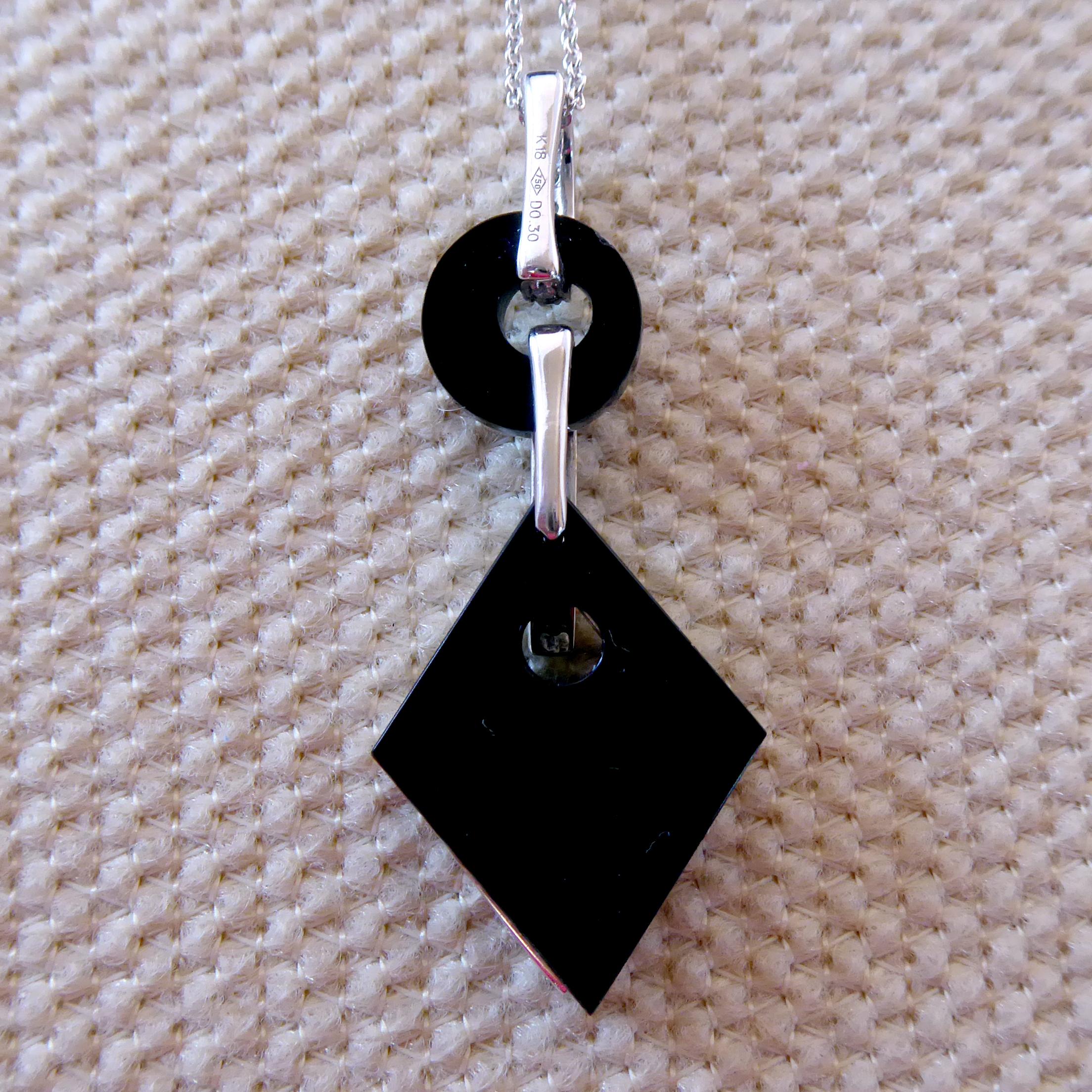 A fabulous pendant crafted in the Art Deco style in a abstract pattern.  A diamond shaped black onyx panel is topped with an open diamond set and diamond shape which forms a frame to the onyx below. Suspending from an oval diamond loop to a circular