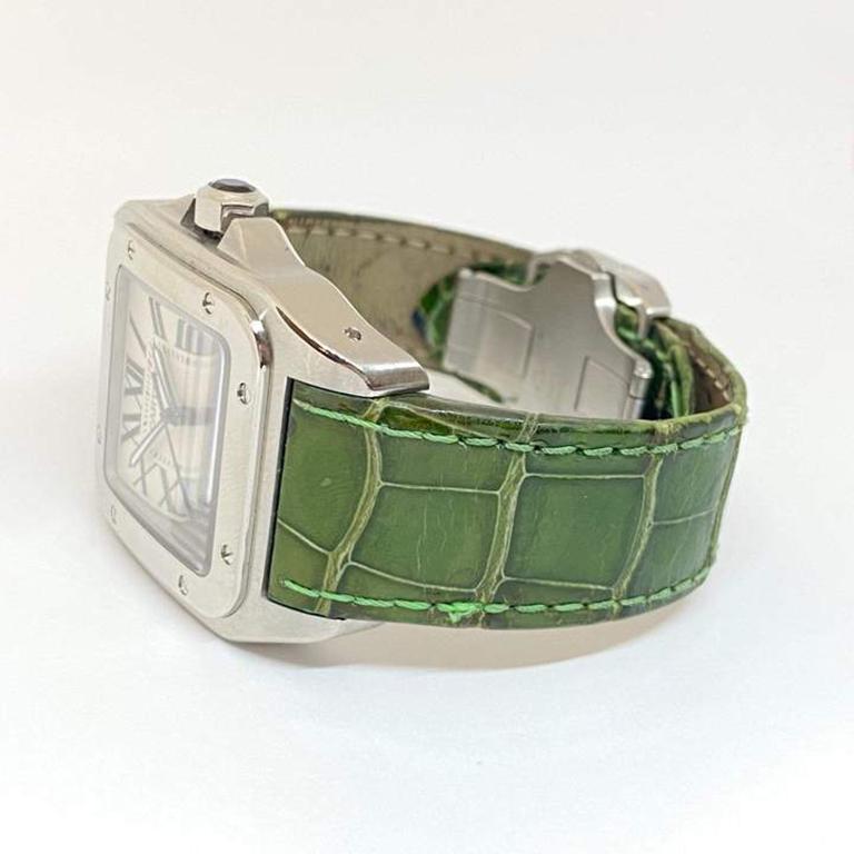 Cartier Santos 100 d'occasion, conçue en acier inoxydable et attachée à un bracelet en cuir Cartier vert vibrant. La montre mesure 38 mm, chiffres romains et trotteuse. Garantie d'un an et en excellent état comme neuf. Numéro de référence 2656.