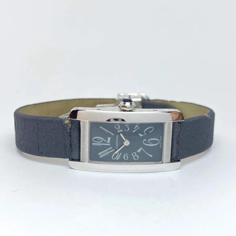 Pre-owned lady's small Cartier Tank Americaine designed in 18 karat white gold. The watch measures 19 x 34.5mm, faceted blue crown, arabic numerals, grey dial, no second hand. Cartier satin grey leather strap, never worn but aged due to heat. See
