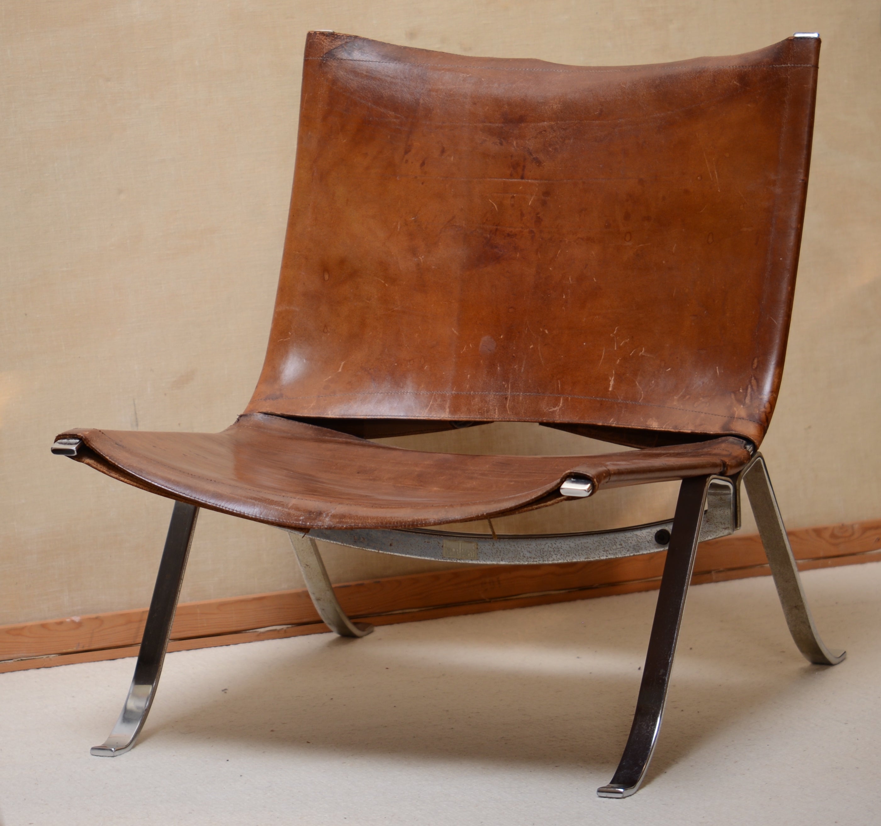This is an unusual lounge chair made of thick leather that has beautifully patinated with years. The frame is made of thick steal with nickel as finish. there's some traces of time that we decided to keep and not clean but it can shine even more