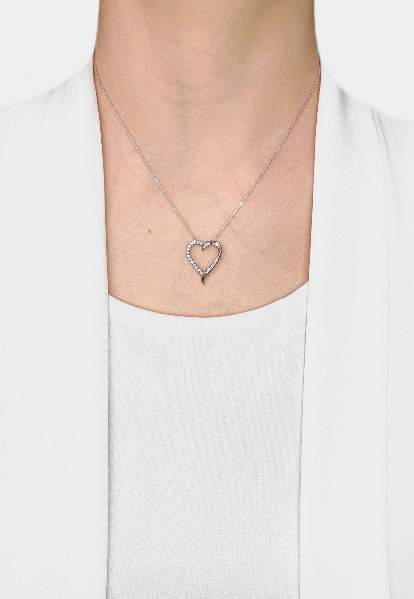 Tombez amoureux de ce pendentif romantique en forme de cœur en diamant, magnifiquement réalisé en or blanc 18 carats. Le design en cœur ouvert est orné de 14 diamants ronds naturels de taille brillant, totalisant 0,28ct, de couleur G-H et de pureté