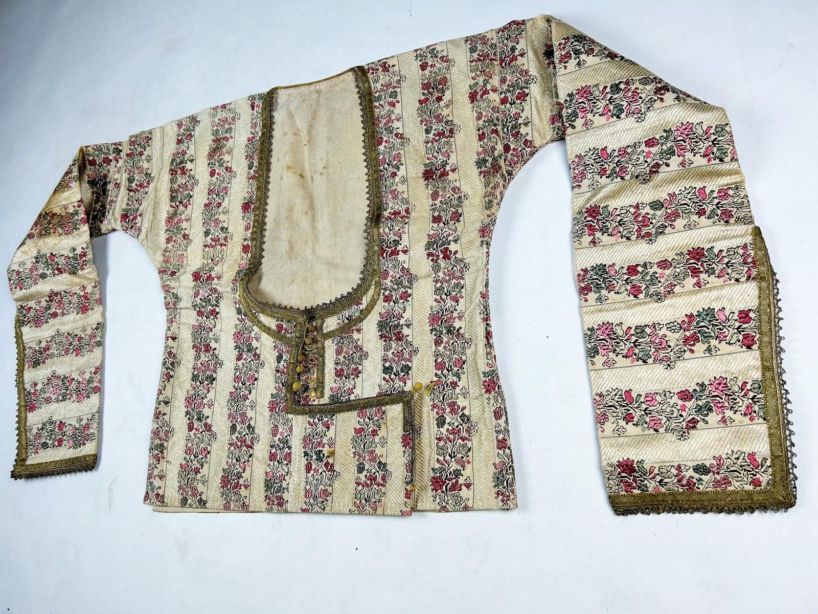 Late 18th or early 19th century
Persia or India
A precious ceremonial bodice in brocaded silk lampas, Moghul or Persian India, dating from the late 18th or early 19th century. Women's cutaway jacket with long roll-up sleeves. Lampas in a brocaded