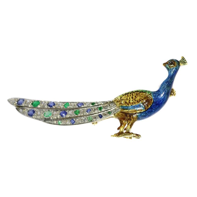 A charming peacock bird enameled brooch in 18 karat yellow gold set with eight natural sapphires, nine natural emeralds, 26 rose cut diamonds and senailles. Dimensions 6,00 cm (2,36 inch) x 3,00 cm (1,18 inch). Weight: 8,50 gram.