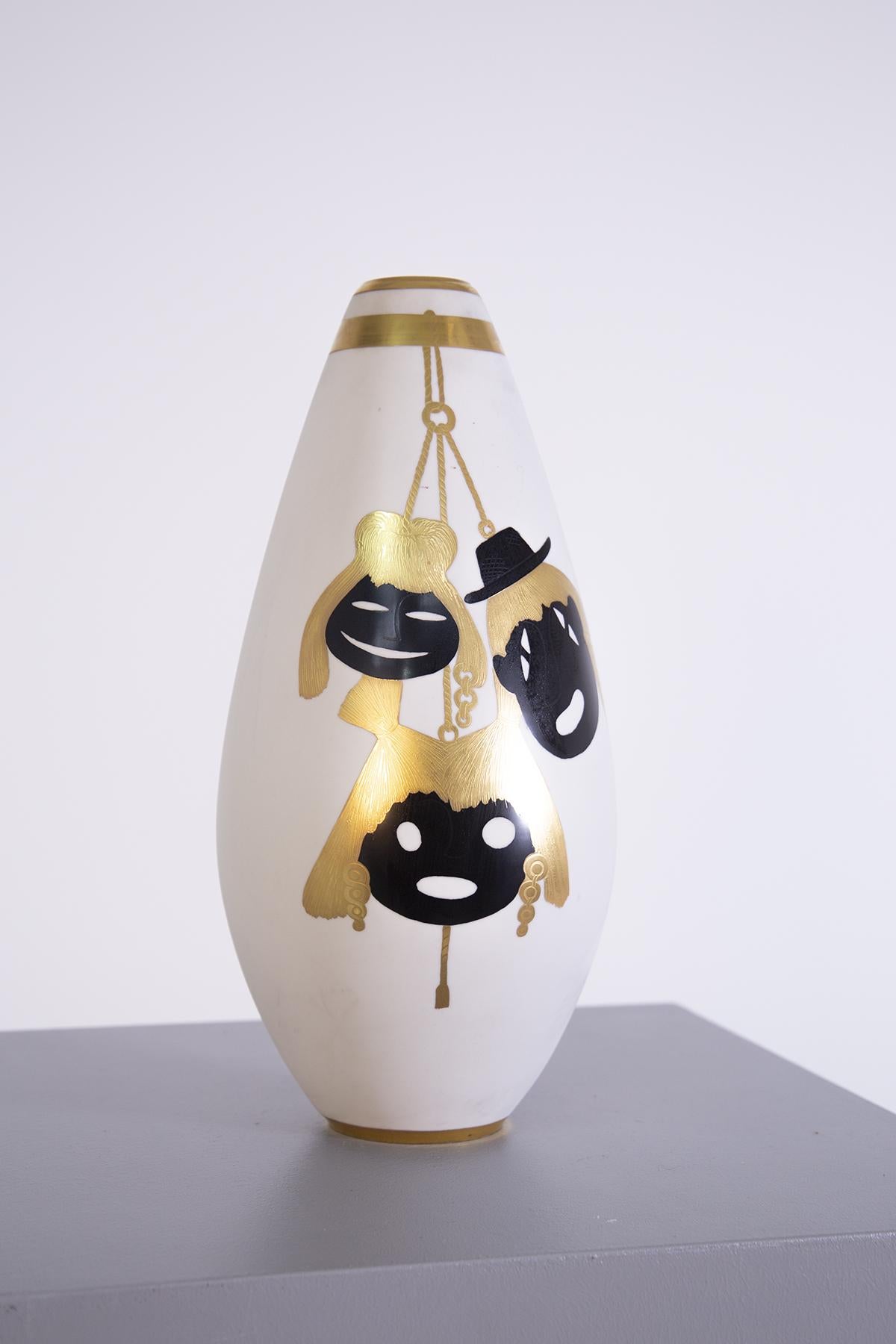 Precious Italian vase from the 1950s made by the great silversmith Arrigio Finzi. The vase has an elliptical shape made in porcelain. Its great particularity are the various elements painted in pure gold. Glie elements depicted are carnival masks