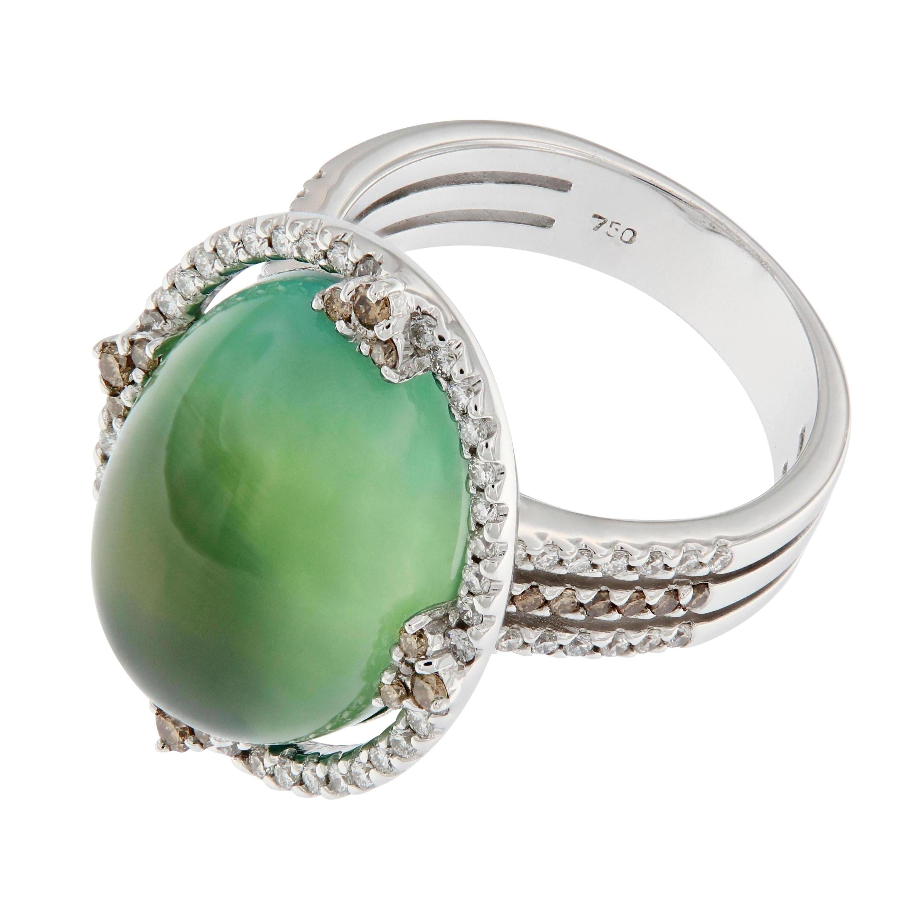 This 18k white gold ring centers around a cabochon cut Prehnite. An intriguing gemstone that features a unique green glow and is known as the stone of prophecy, aiding in spiritual communication through meditation. Center stone is accented with