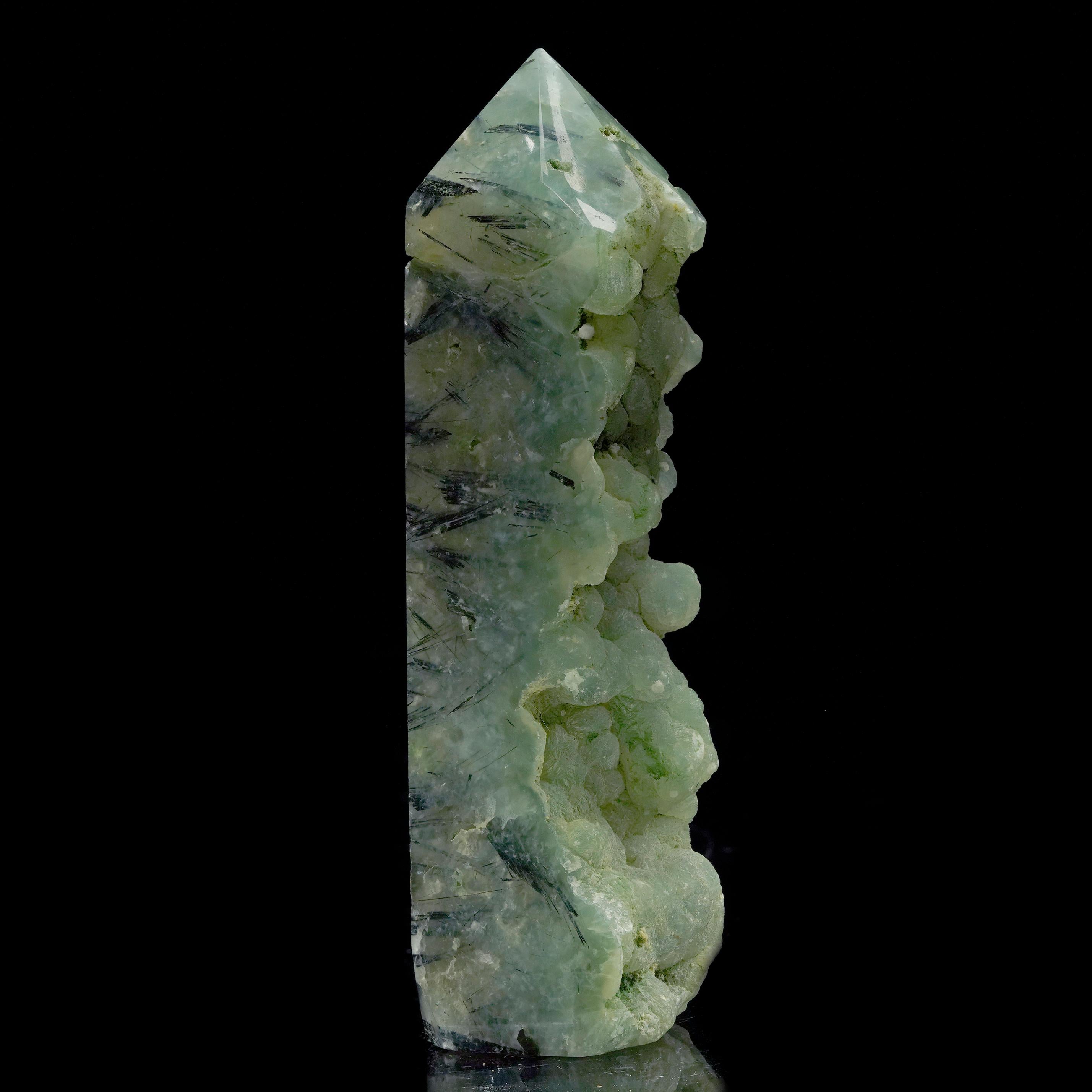 Questa singolare torre è stata scolpita a mano da un esemplare di prehnite di dimensioni significative proveniente dal Mali. I suoi verdi screziati e terrosi e la sua ipnotizzante traslucenza mostrano le inclusioni di Epidoto aghiformi all'interno.