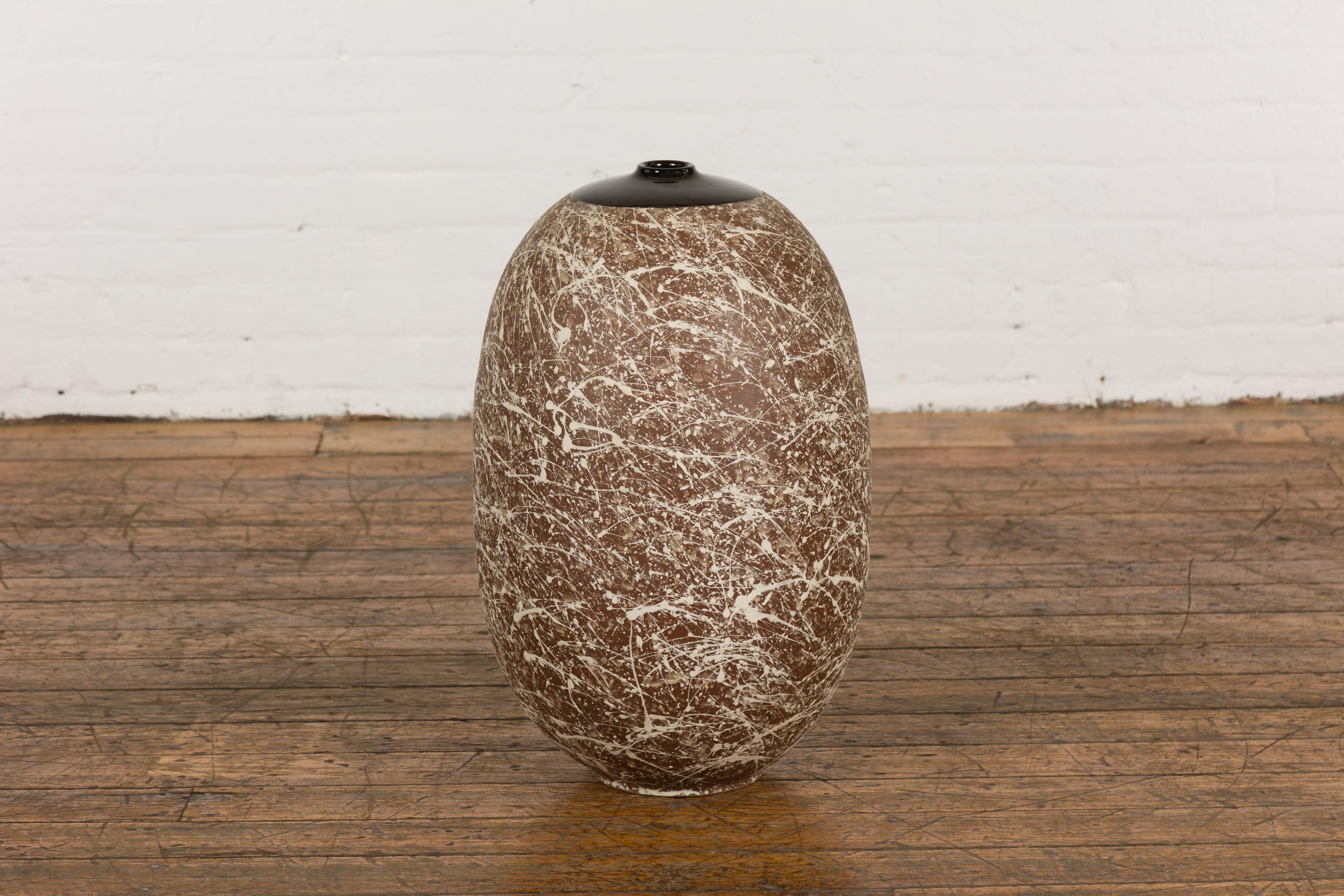 A large contemporary Prem Collection artisan hand crafted ceramic vase or object with narrow mouth, brown ground, energetic hand-painted beige dripping décor, black glazed top and rounded tapering lines. Emanating an engaging blend of modern