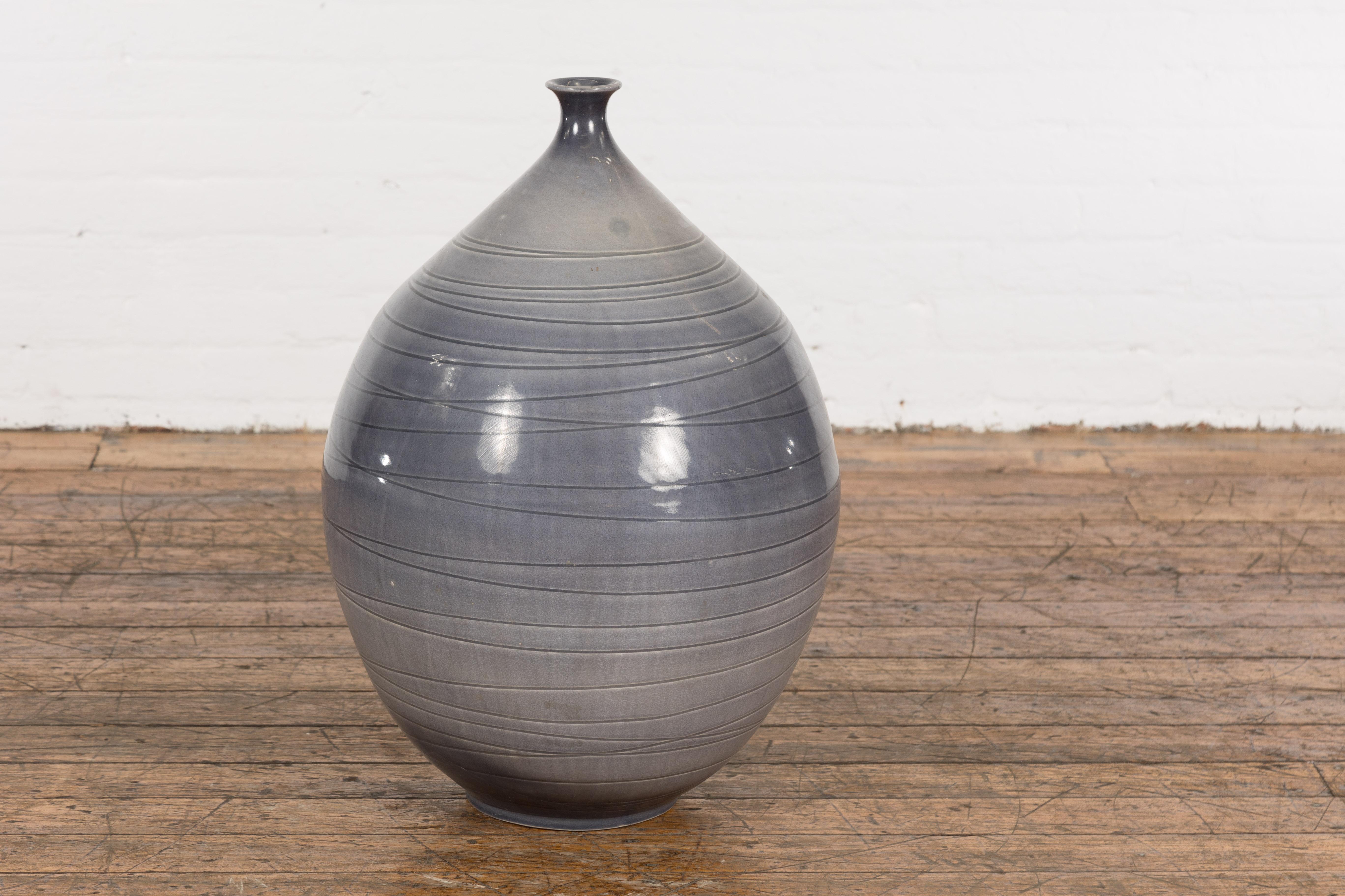 A contemporary Prem Collection artisan hand crafted ceramic vase with narrow mouth, blue grey glaze and striated effects. Showcasing elegant lines, this hand crafted Prem Collection artisan ceramic vase features a blue grey glaze beautifully