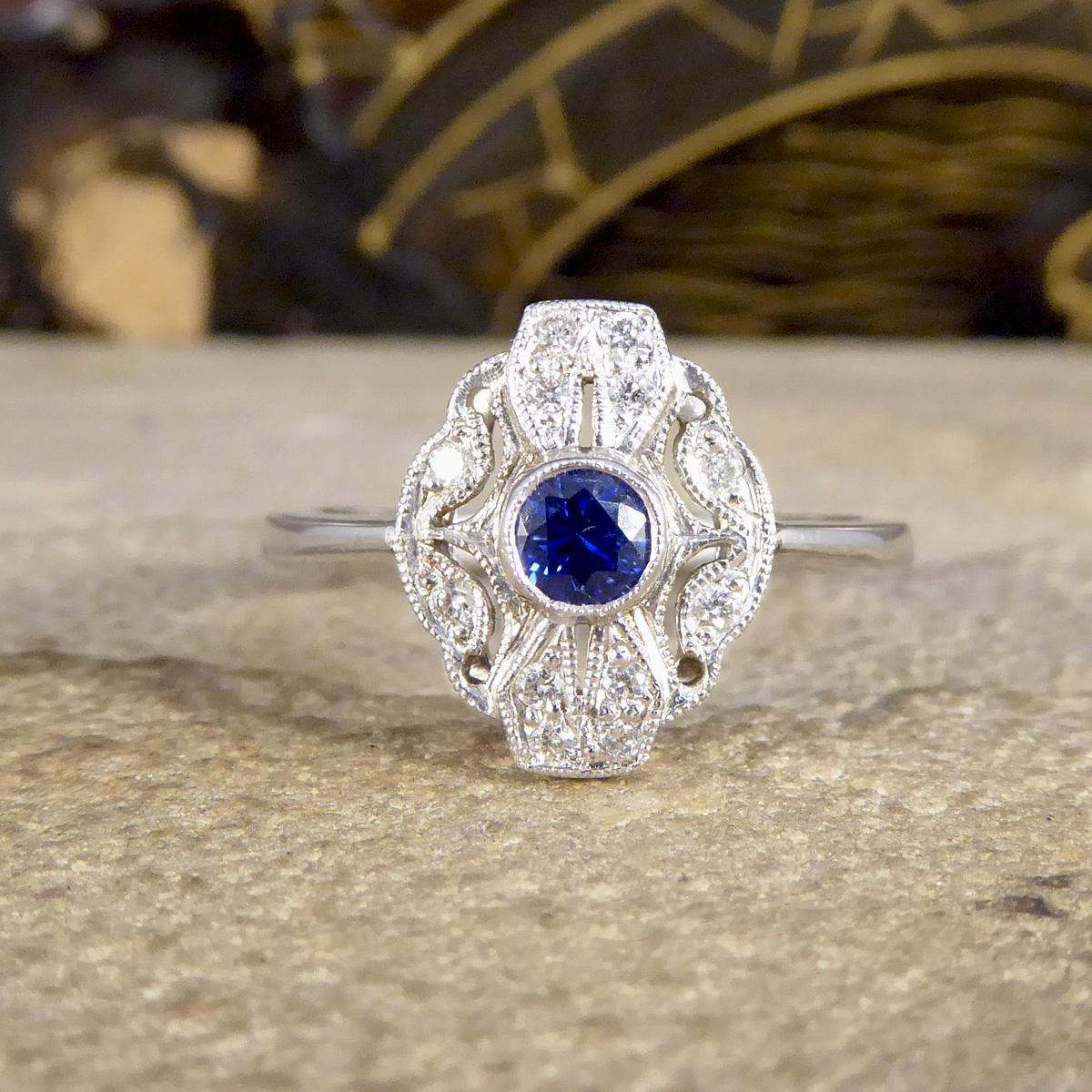 This stunning ring has been hand crafted and is new and never worn. It has been designed and carefully crafted to resemble an Art Deco style ring with a collar set bright Blue Sapphire weighing 0.27ct in the centre with a milgrain edge surrounded by