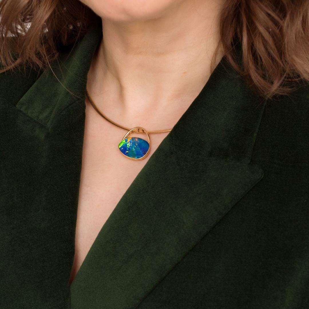 The captivating ‘Sophia’ opal pendant features a mesmerising blue-green play-of-color captures the vibrant hues of nature, making it a truly captivating piece. This extraordinary pendant showcases a magnificent 9.31ct doublet black opal set in 18K
