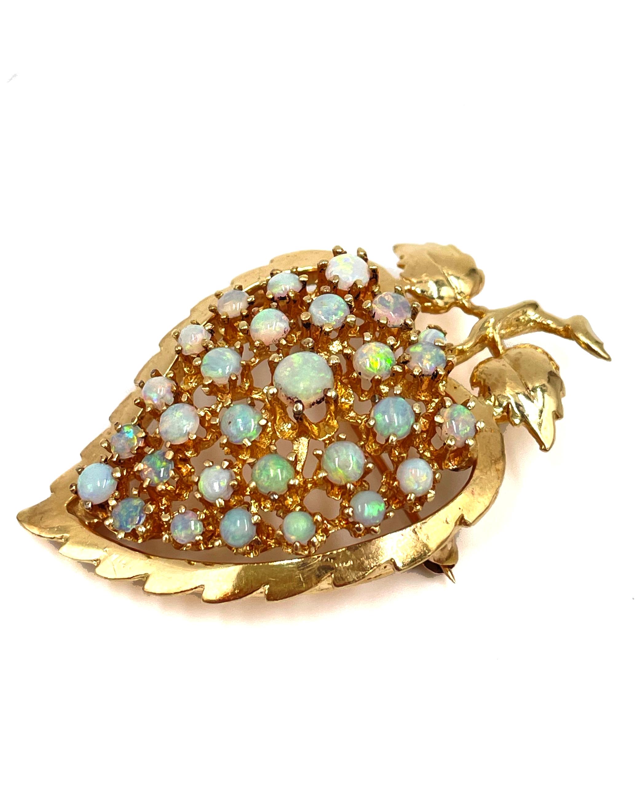 Preowned 14K yellow gold leaf shaped brooch pin/ pendant furnished with 29 opals. The opals are blue/green iridescent color. The sizes range from 2.4mm to 4.2mm. The brooch is in very good working condition with light scratches all around. 

Two