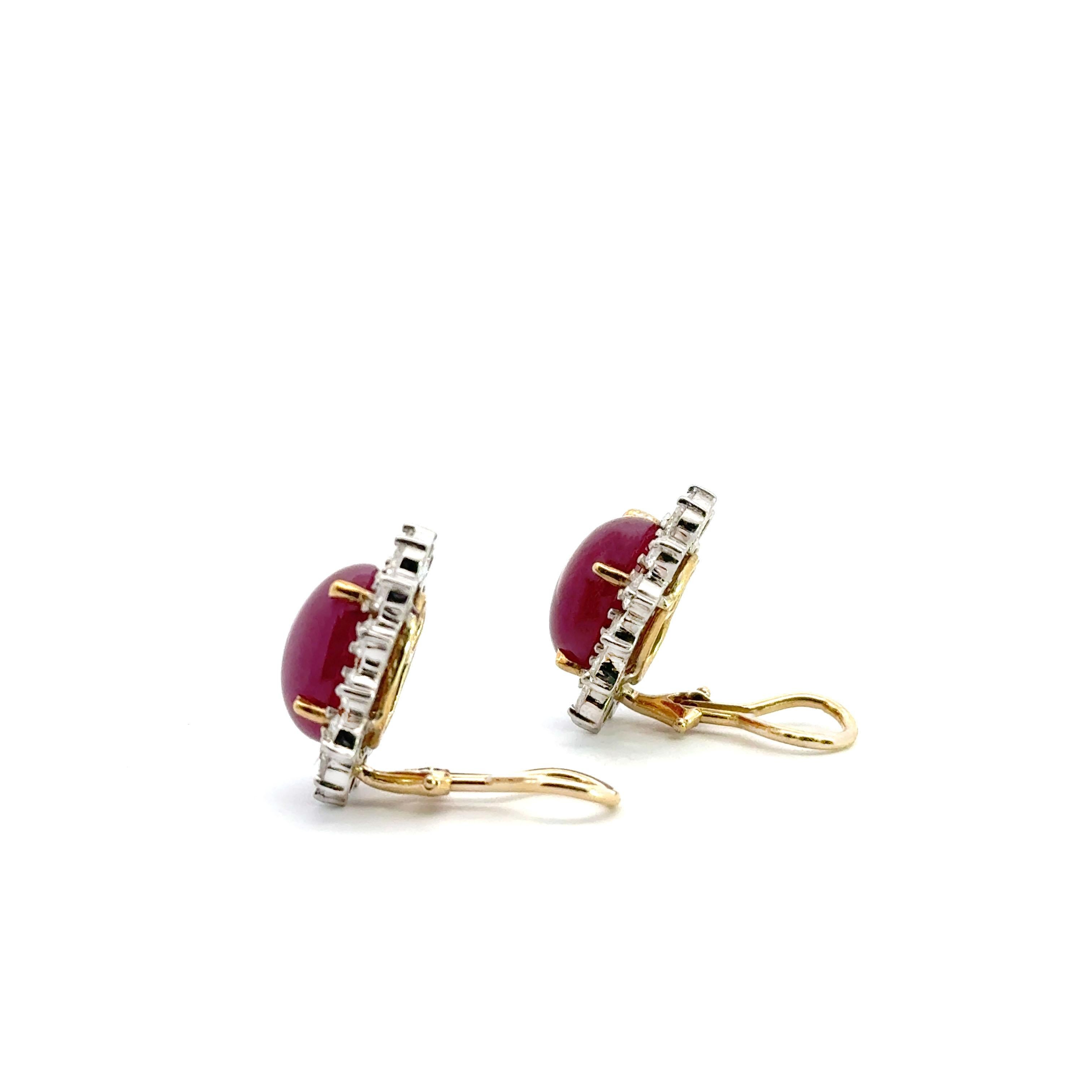 Preowned 14K yellow gold clip on button earrings featuring two oval shaped cabochon rubies measuring approximately 14.2x11mm and weighing approximately 15 carats total.  The rubies are surrounded by 25 round brilliant-cut diamonds weighing