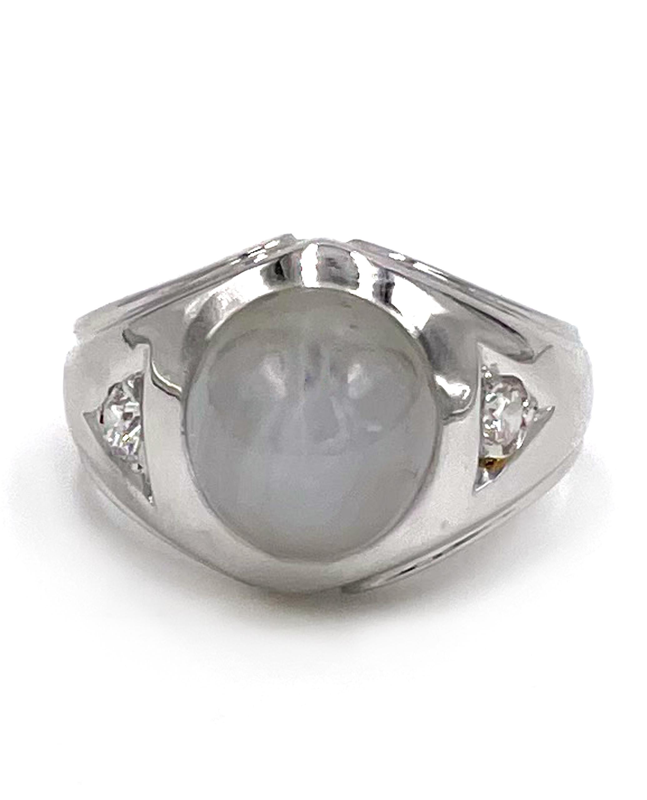 Preowned vintage 14K white gold flush set ring with one oval shape grey color star sapphire and two round side diamonds approximately 0.12 carat. 

* Finger size 5.75.
* Star sapphire is approximately 10.00mmx9.35mm
* Top width 13.44mm - tapers down