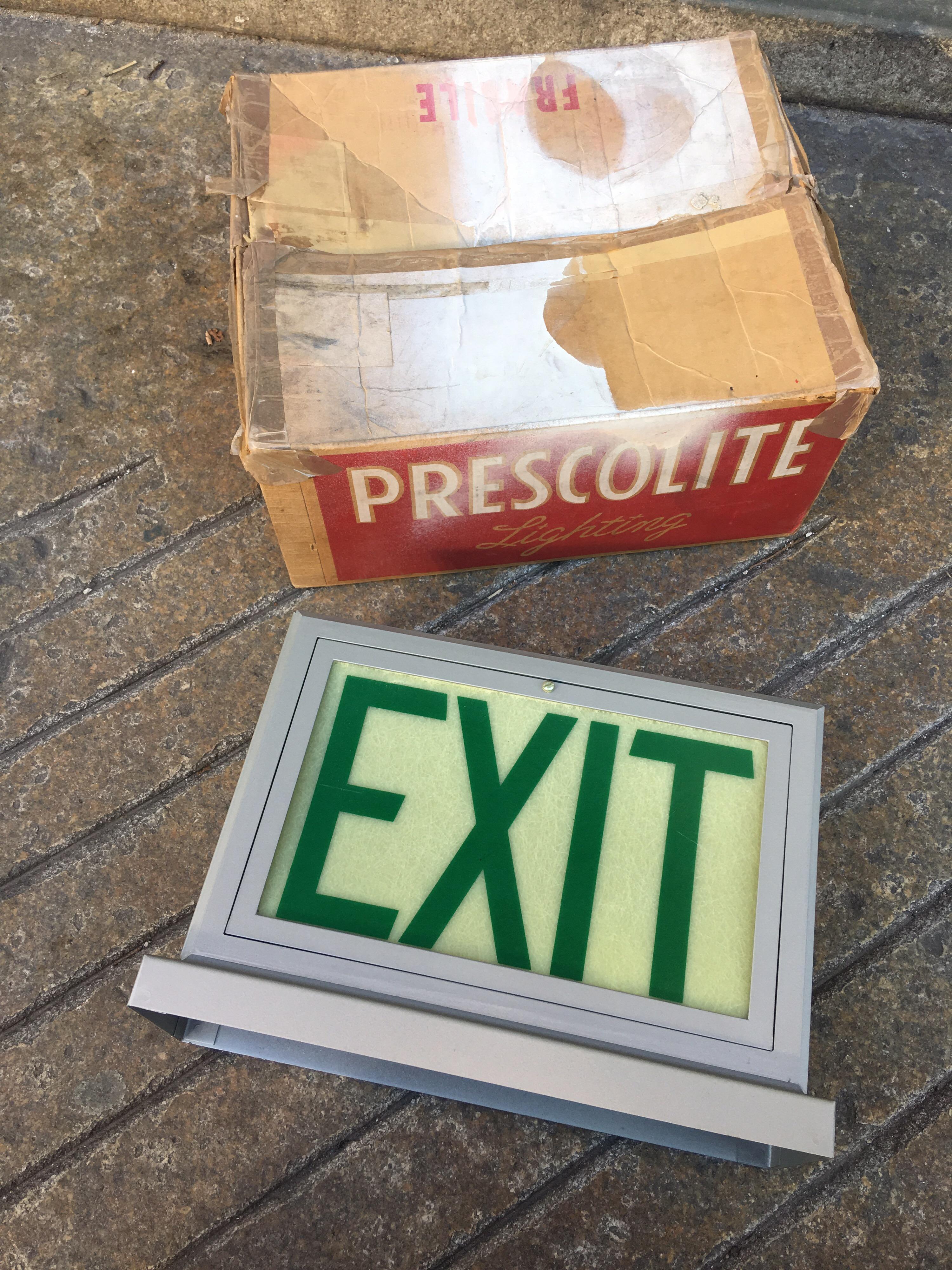 We all need a great exit! NOS Prescolite Fiberglass Exit Sign! Can be hung from a ceiling or put upon a ledge! Never used! Perfect condition! Box shows some wear, but light is in very nice condition! Great original decals!