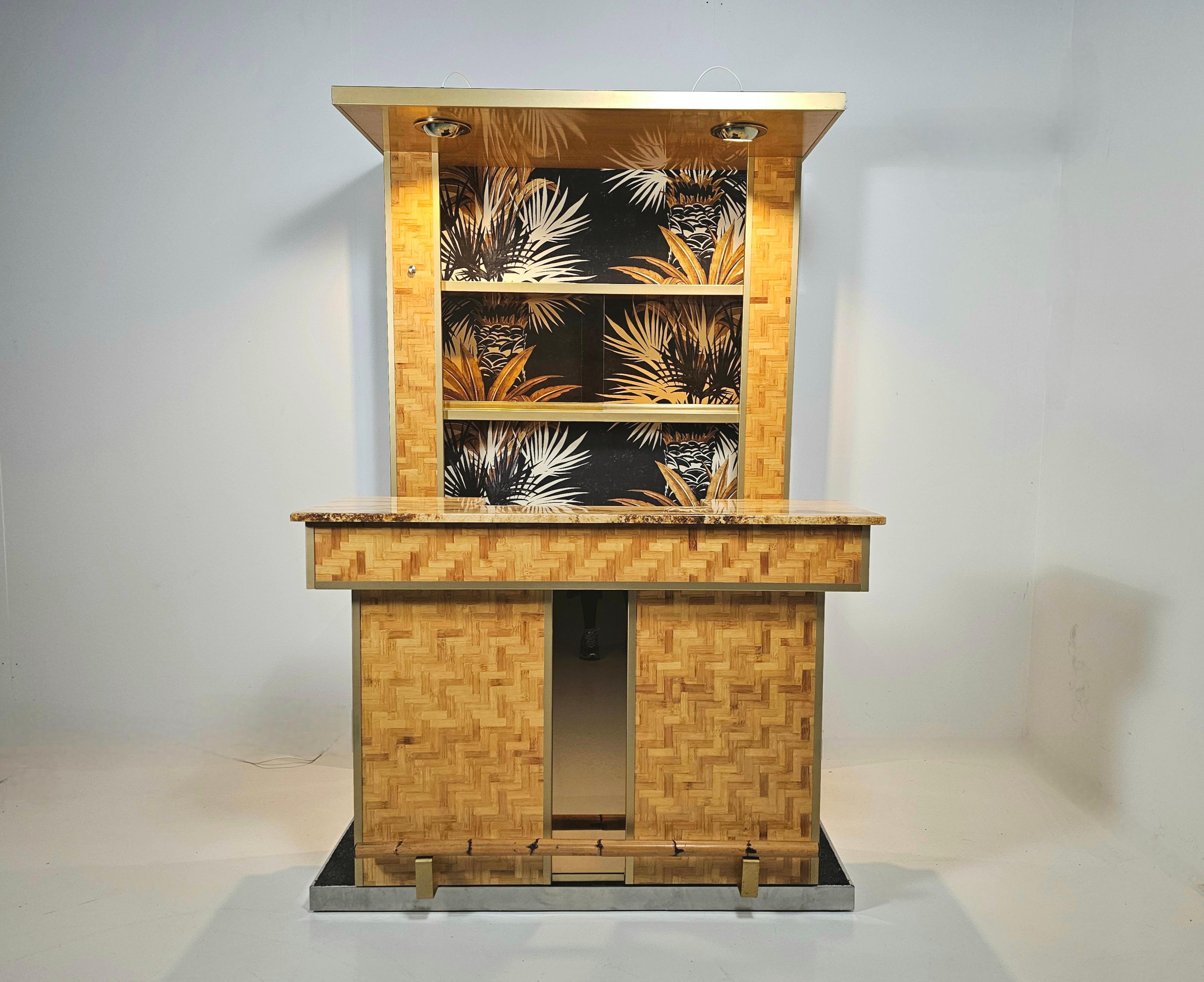 Cocktail bar with bar stools, brass, pressed bamboo,  smoked mirrored glass, and marble, Italy, 1970s

Unique Hollywood Regency cocktail bar. The counter contains two doors, 2 drawers and shelfs.  The back has shelves and smoked glass sliding doors.
