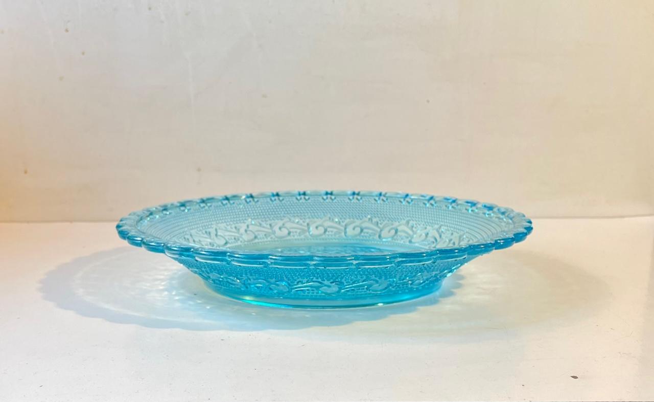 A rare pressed glass dish in uranium or vaseline blue - the most vibrant mint blue. Decorated with waves, dots and diamond patterns. Made at Fyns Glasværk/ (later) Holmegaard circa 1930. Measurements: D: 30 cm, H: 5 cm.